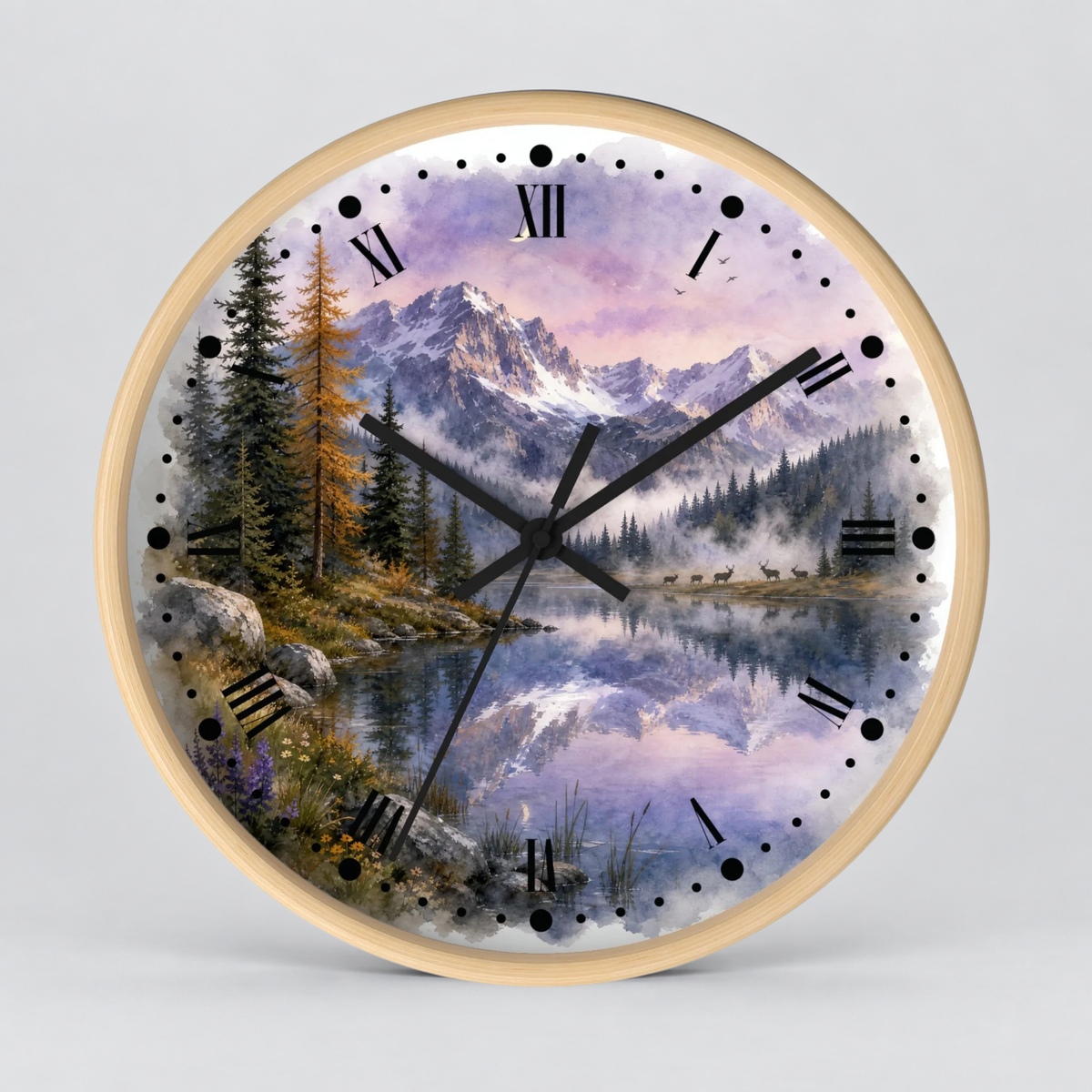 A round wall clock with a light wood frame and a scenic landscape print featuring a mountain lake, evergreen trees, a herd of deer, and a purple-lavender sky. The clock face has black Roman numerals and black hands on a light gray background.