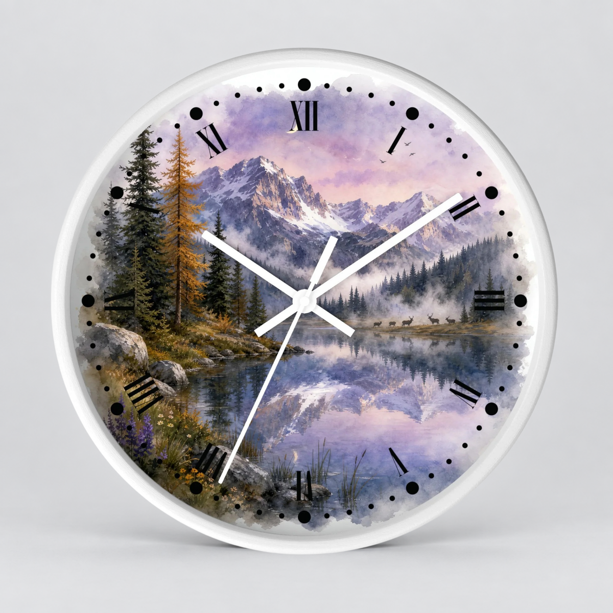 A round wall clock with a white frame and a scenic landscape print featuring mountains, pine trees, a reflective lake, , a herd of deer, and a soft purple dusk sky. The clock face uses black Roman numerals and black dot hour markers, with white clock hands at the center.