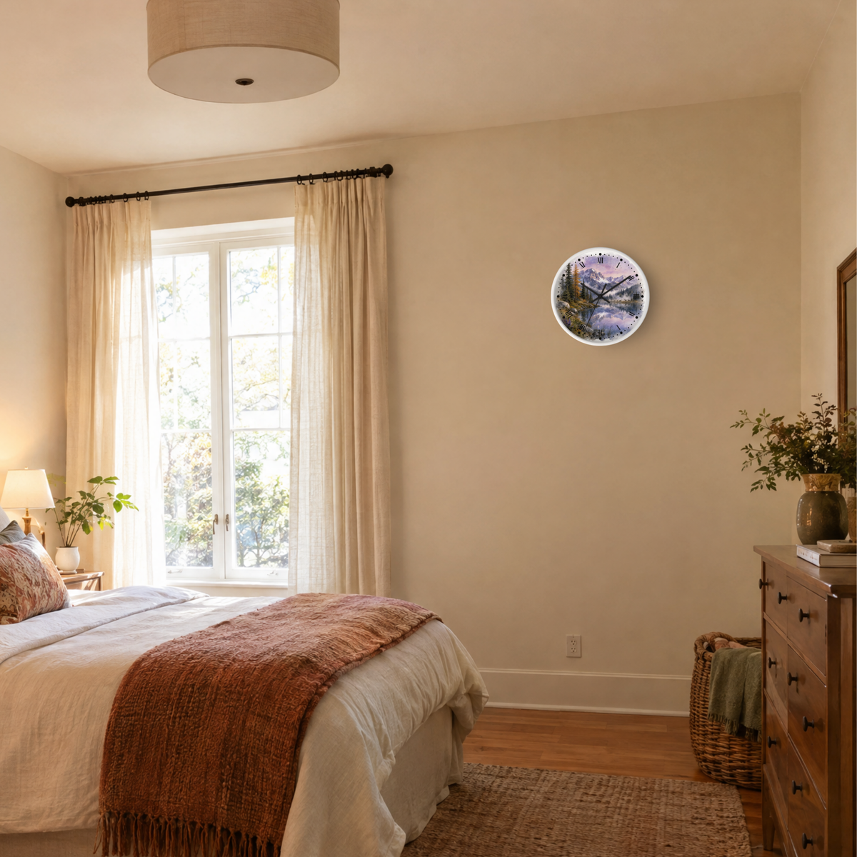 A round wall clock with a scenic mountain landscape print is mounted on a beige wall in a styled bedroom setting with a bed, window, and wooden dresser.
