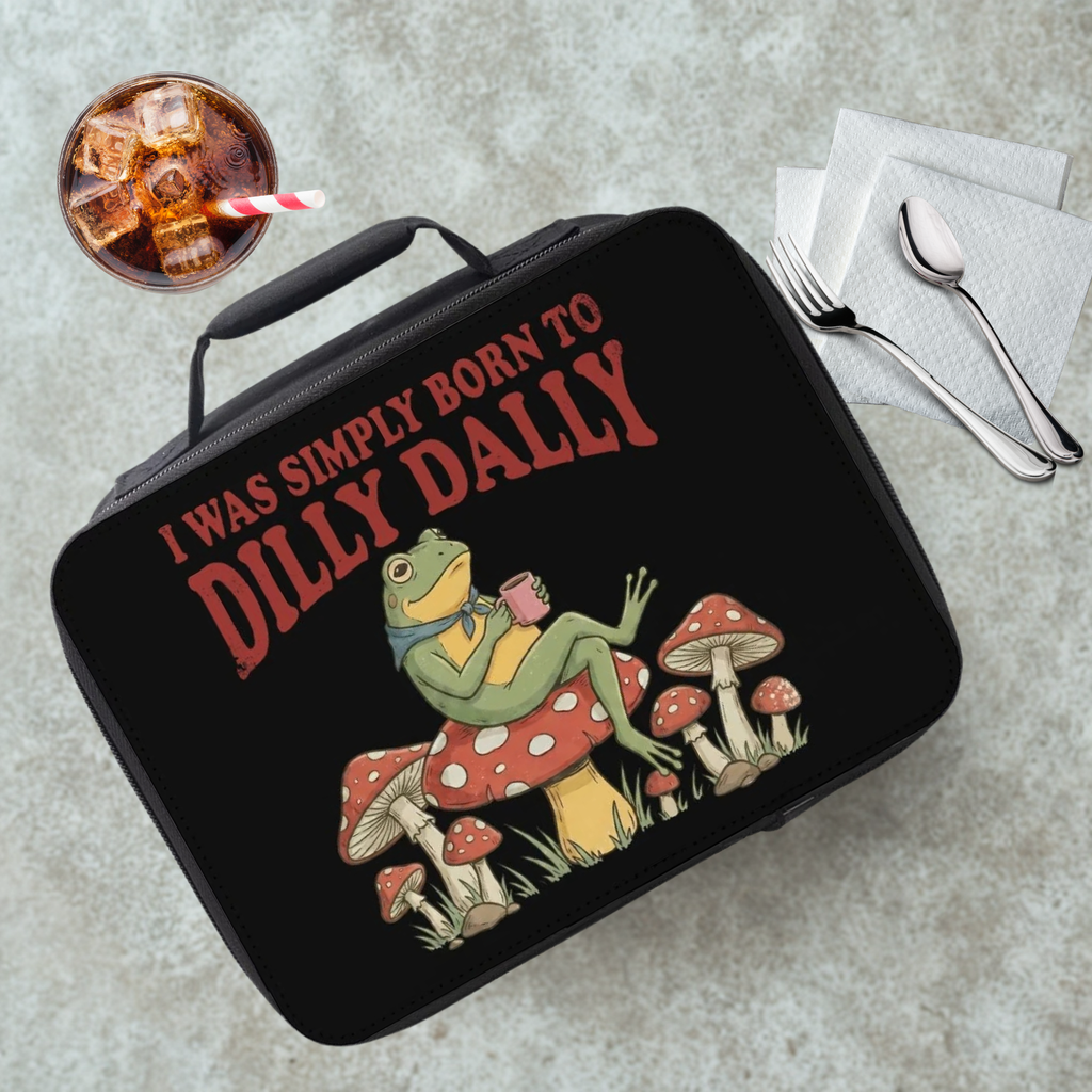 Black lunch box with a frog graphic and text on a gray table with a drink and utensils.