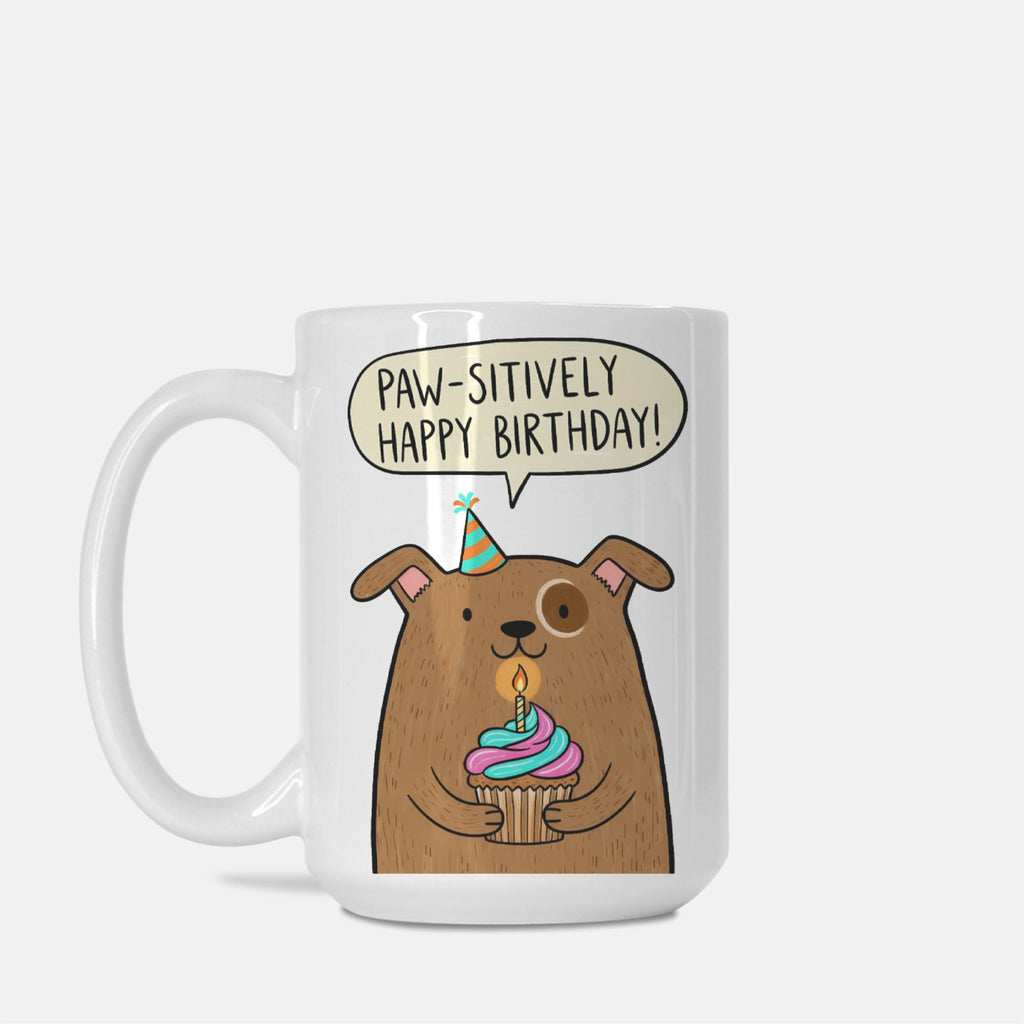 Mug with a cartoon dog holding a birthday cupcake and a speech bubble saying 'Paw-sitively Happy Birthday!' on a white background.