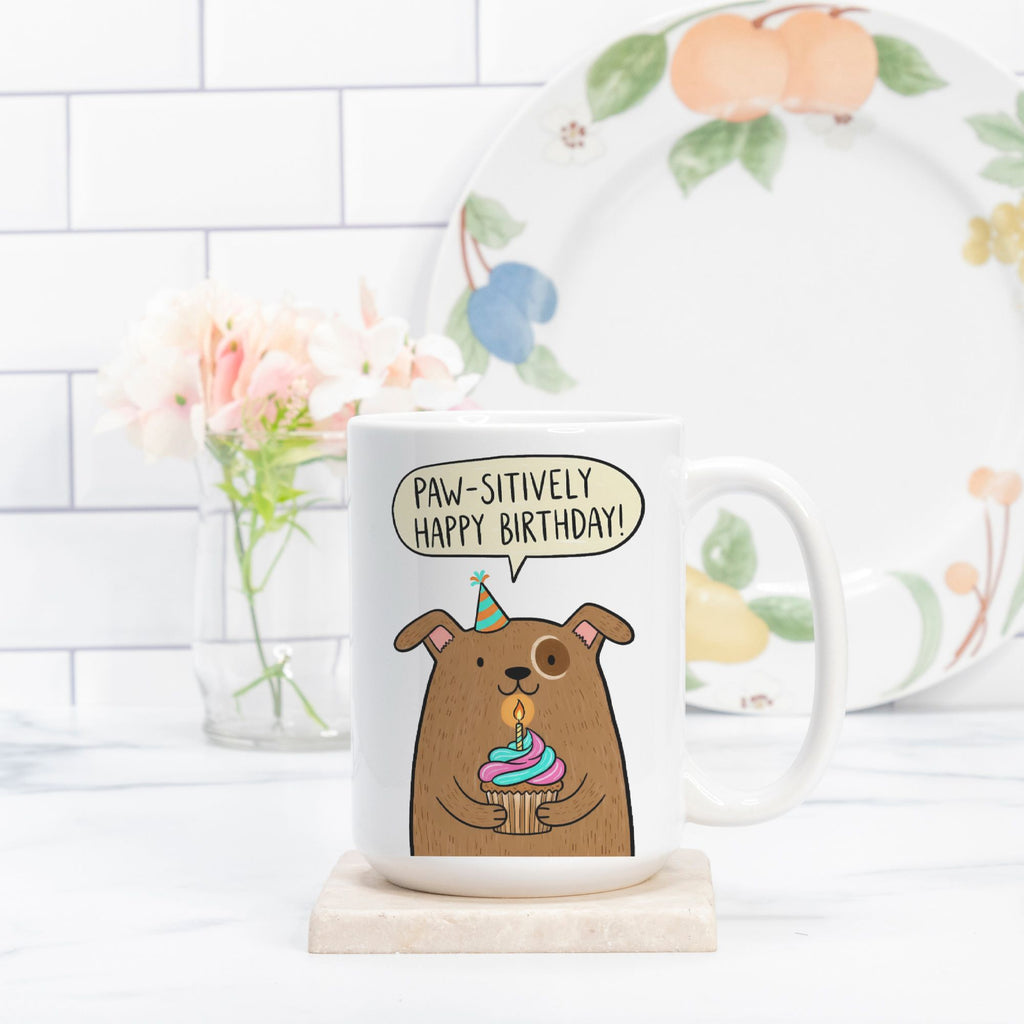 Mug with a cartoon dog and birthday candle design, featuring the text 'Paw-sitively Happy Birthday!'.
