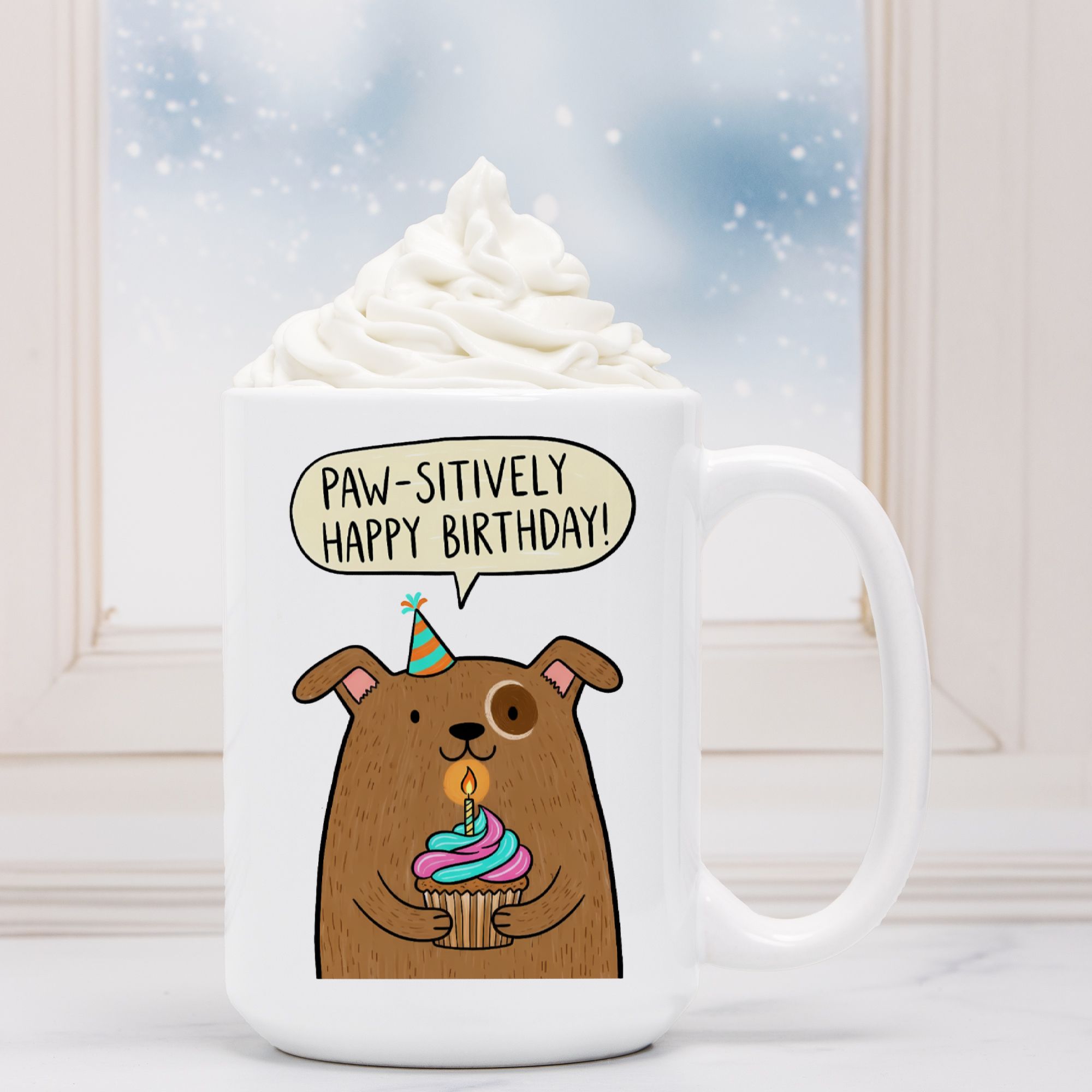 White mug with a cartoon bear holding a birthday cake and a speech bubble saying 'Paw-sitively Happy Birthday!' against a snowy background.