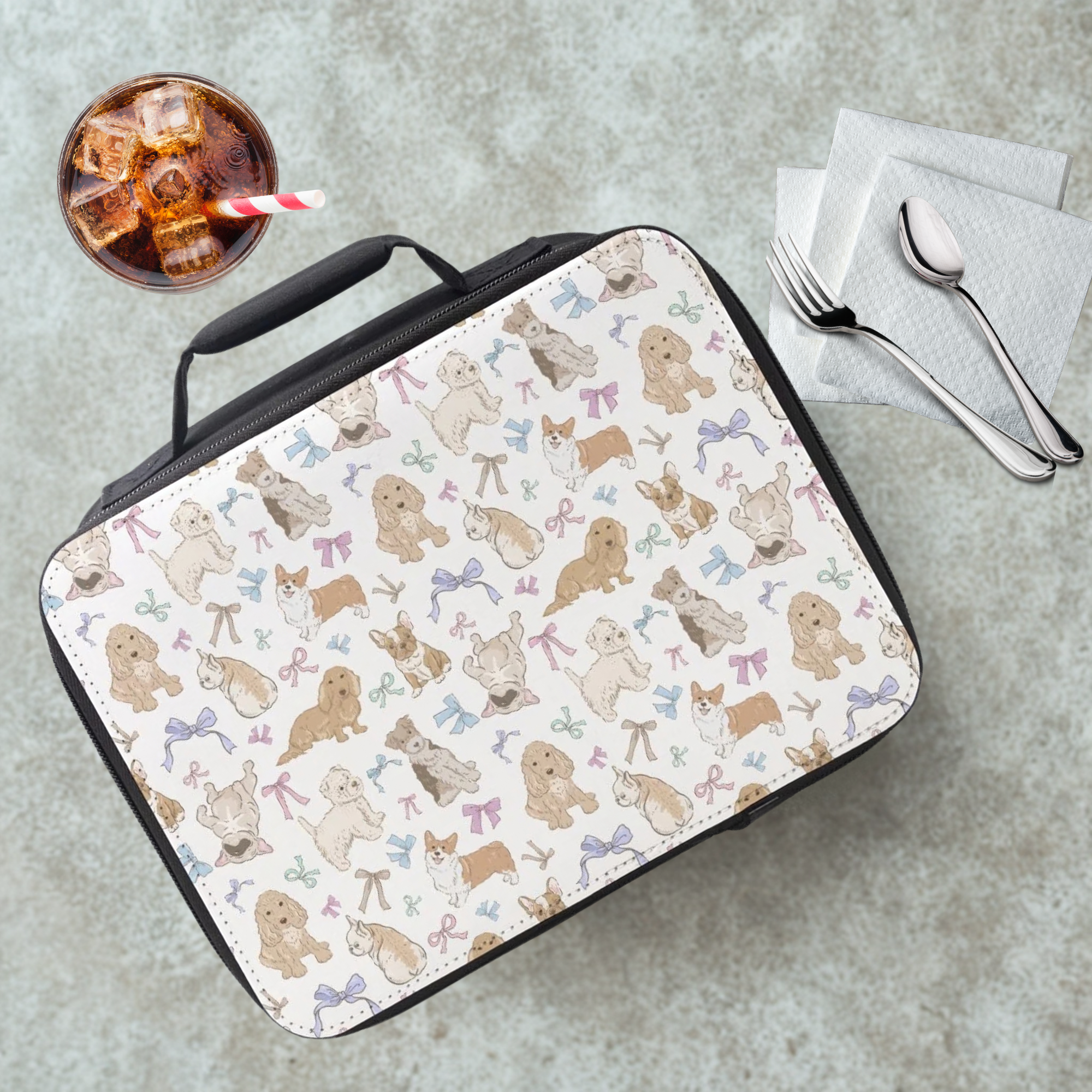 Lunch bag with dog pattern on a cafeteria table with a drink and utensils.