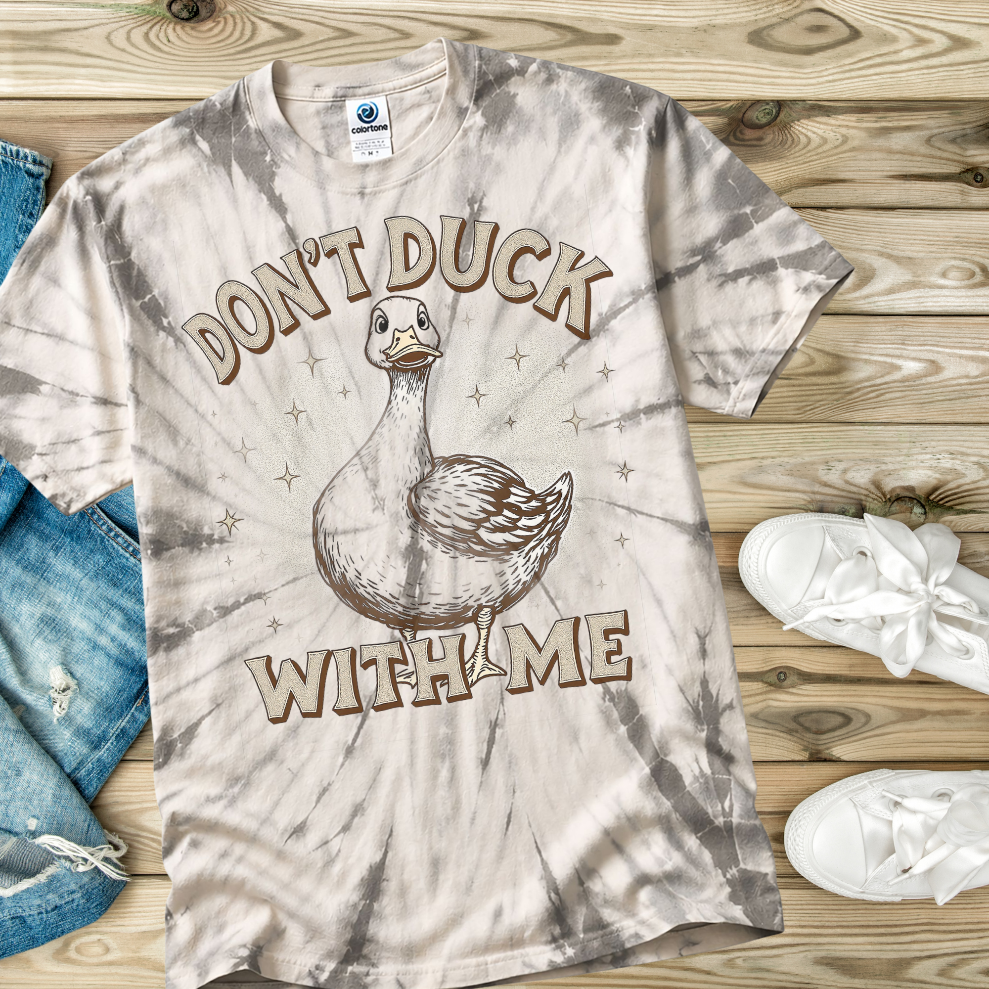 Tie-dye t-shirt with a duck graphic and text 'Don't Duck With Me' on a wooden surface.