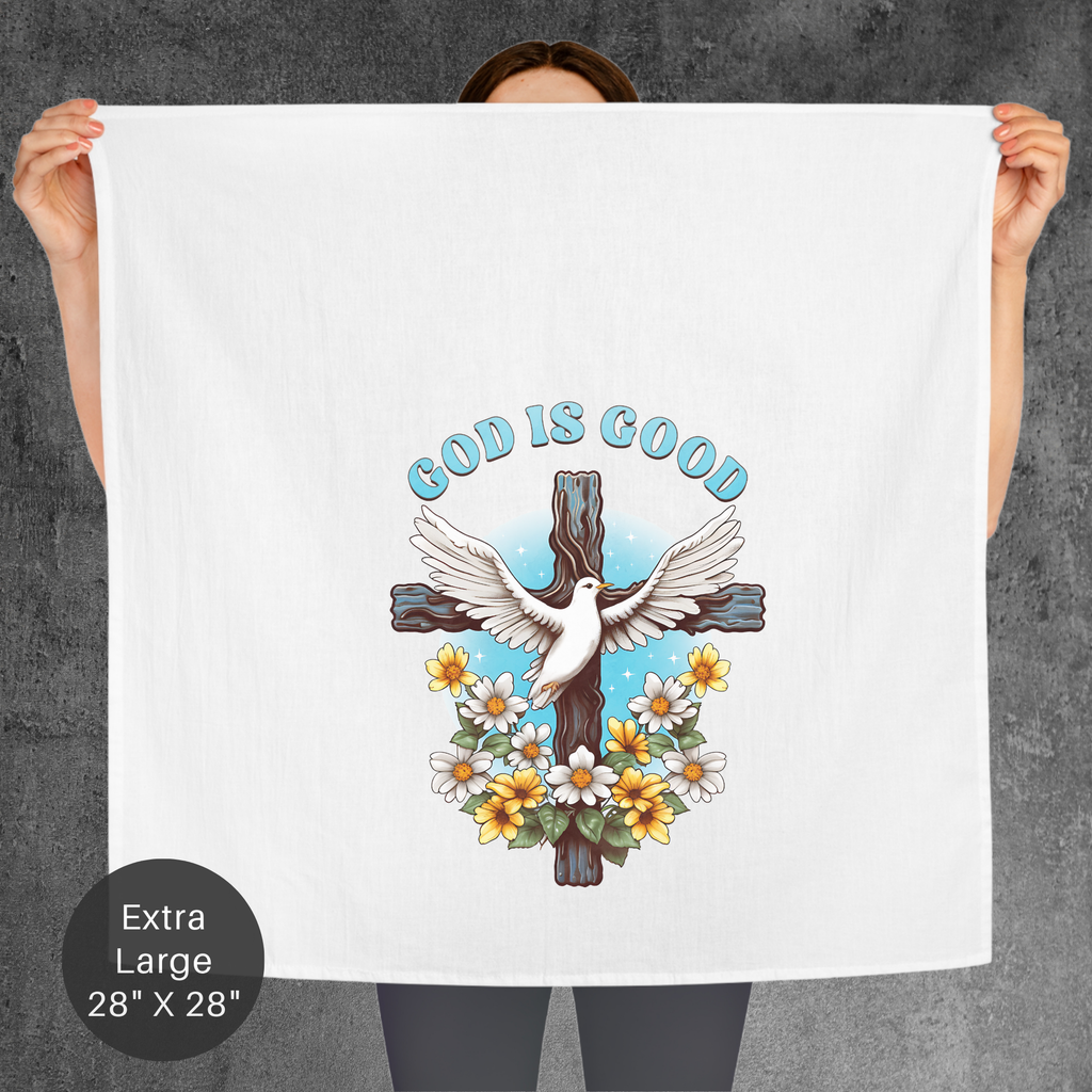 Person holding a towel with a cross, dove, and flowers design and 'God is Good' text.