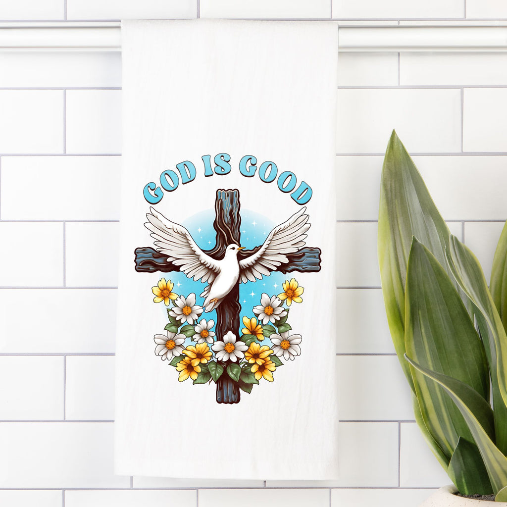 Decorative white tea towel with a cross, dove, and flowers on a white tiled wall.