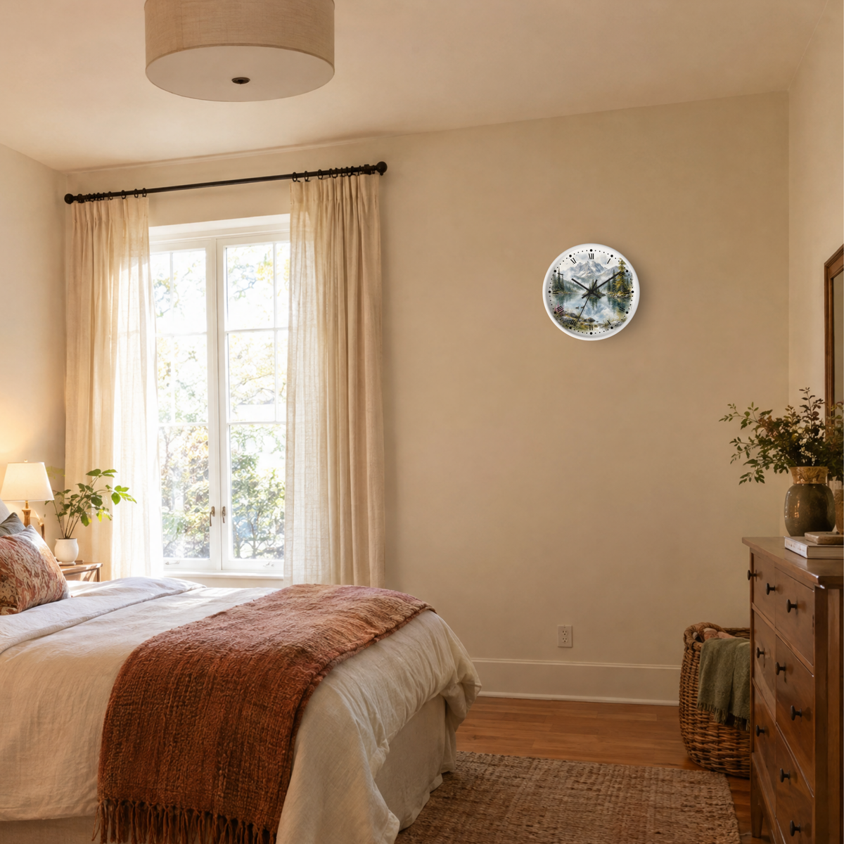 A round wall clock with a blue and white floral mountain lake design and black Roman numerals, mounted on a beige wall in a styled bedroom setting.