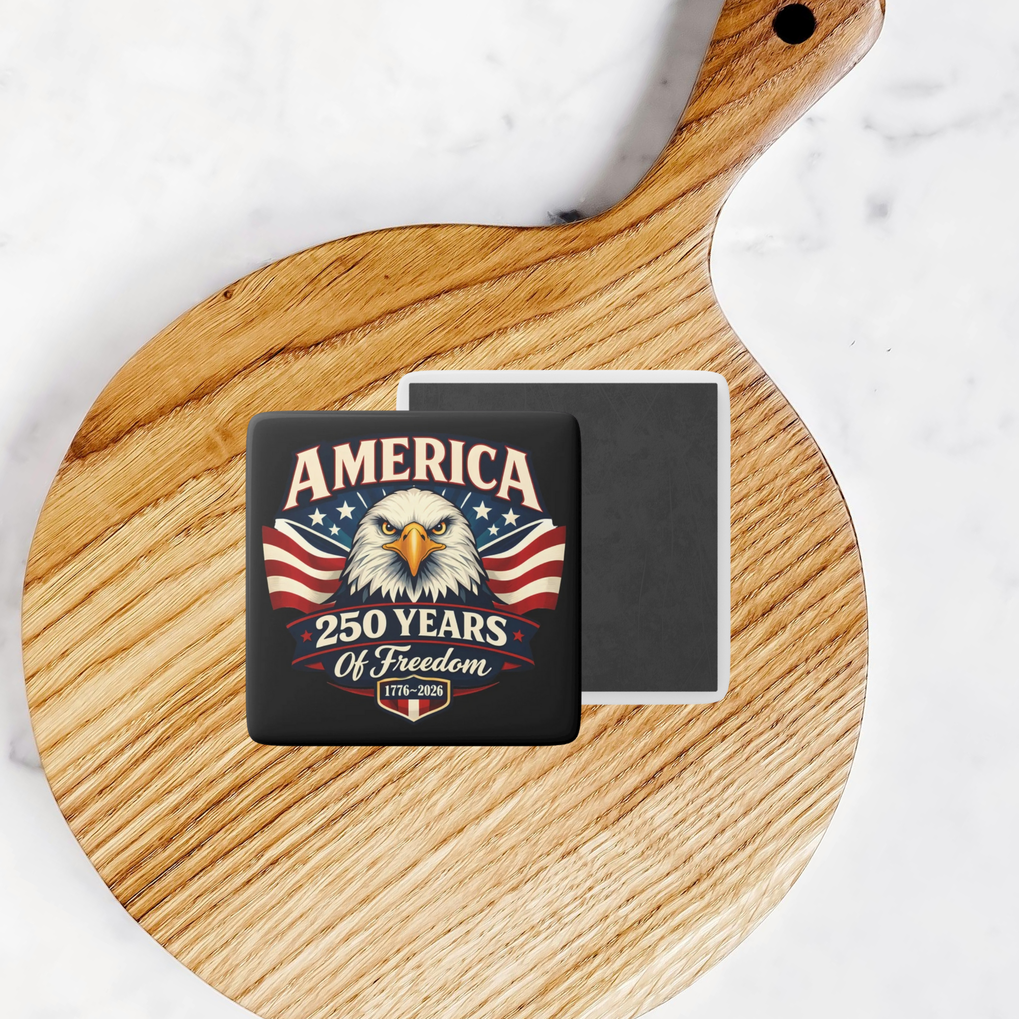 2 inch square porcelain magnet with an Eagle America 250 Years of freedom design on wooden board on counter