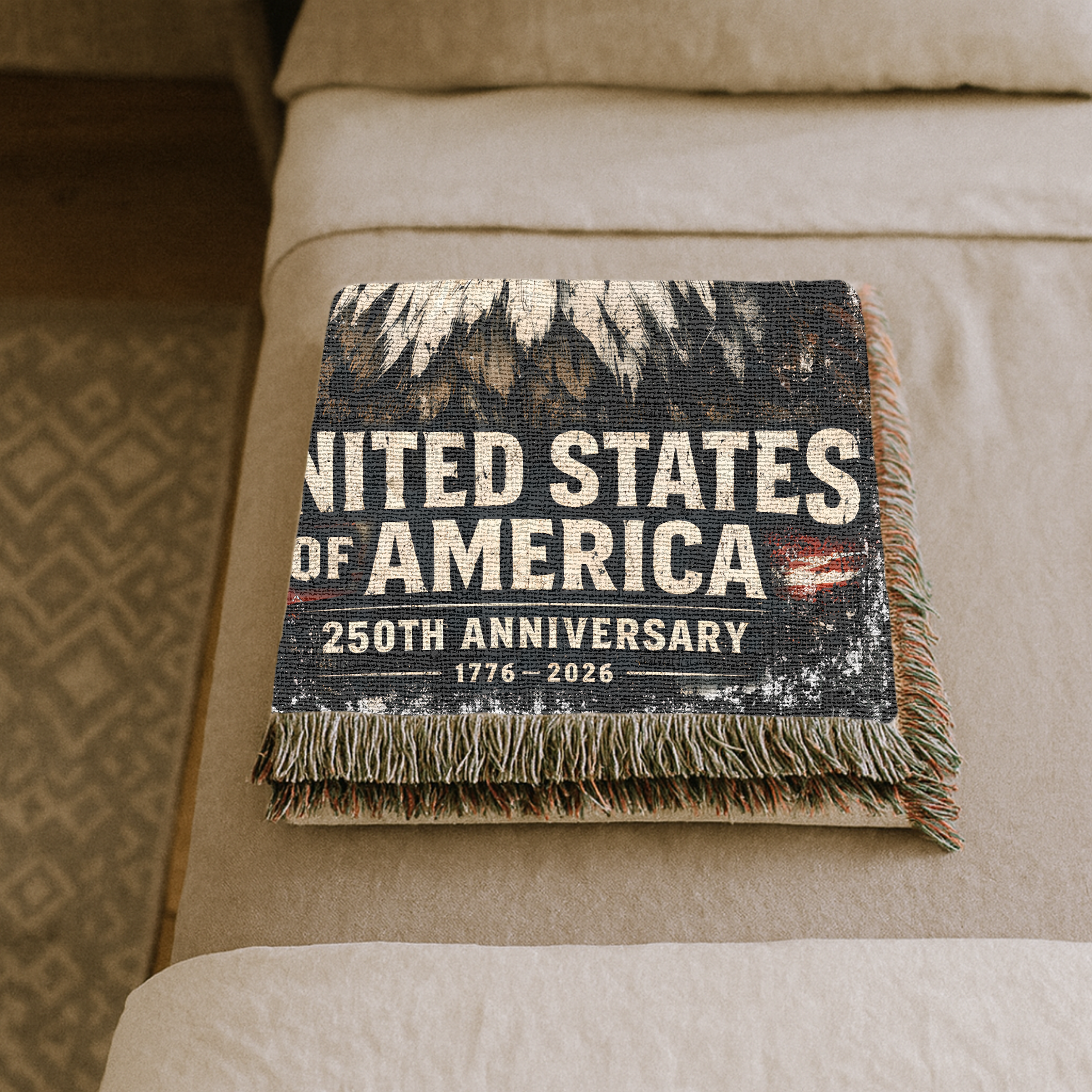 Folded Blanket with 'United States of America 250th Anniversary' text on a beige bed.