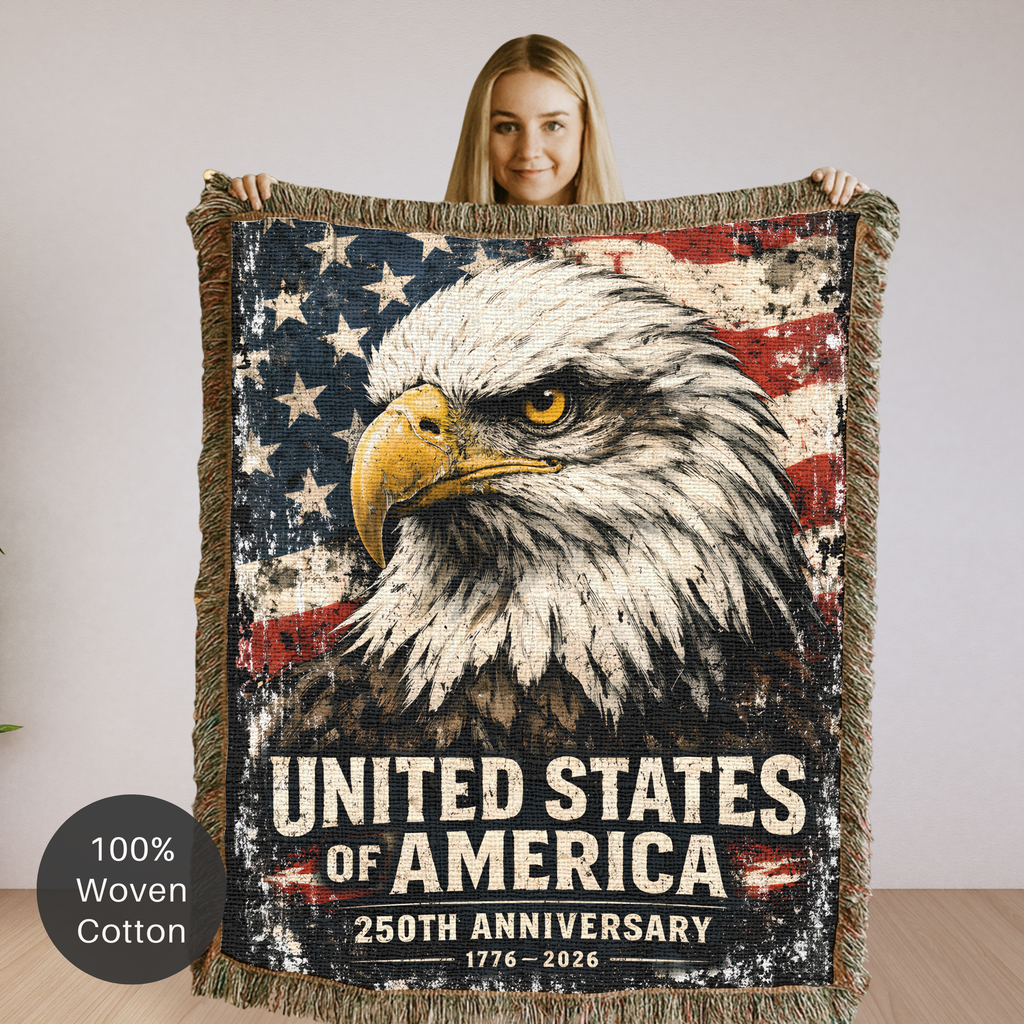 Person holding a woven blanket with an eagle and American flag design, featuring 'United States of America 250th Anniversary' text.