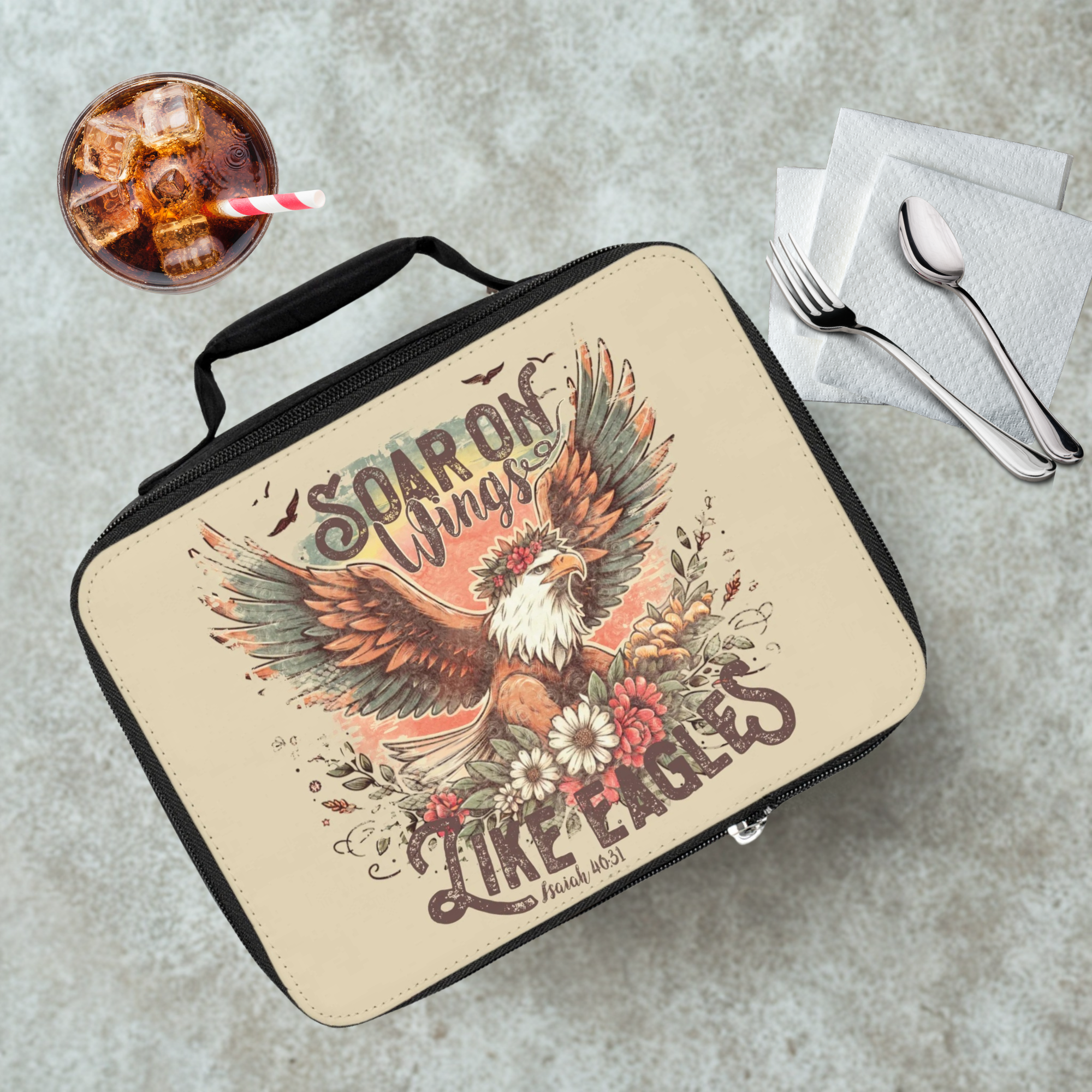 Lunch bag with eagle design and motivational quote on a cafeteria table  with a drink and utensils.