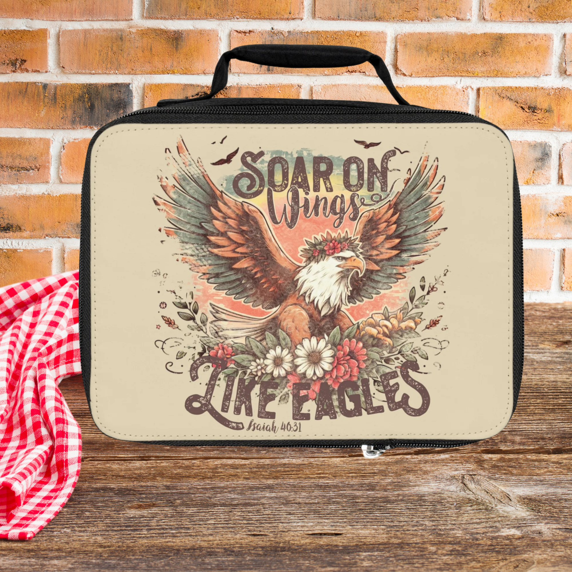  insulated lunch bag with eagle design and text on a wooden picnic table with brick background