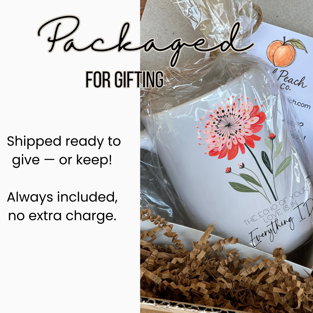 White 15oz mug with floral design and text, wrapped in clear plastic in a white gift box  with brown paper underneath