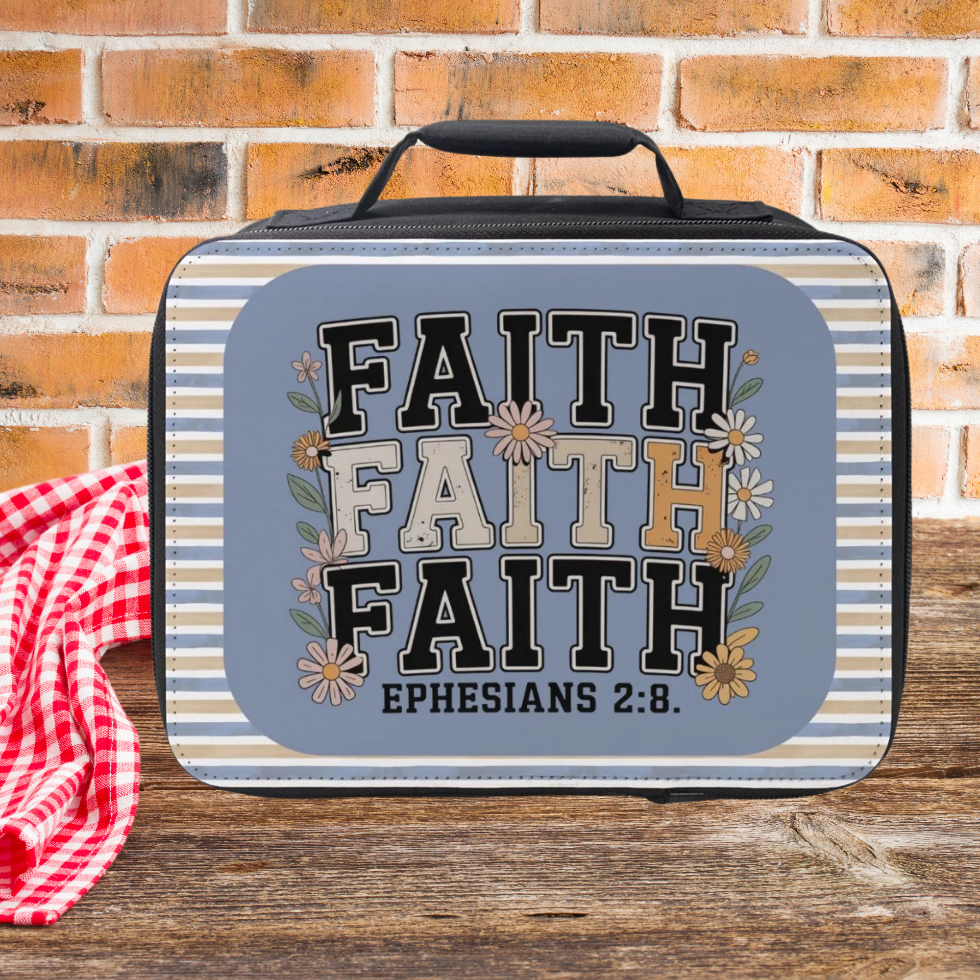 insulated lunch bag with a blue and gold design on a wooden picnic table and brick background.