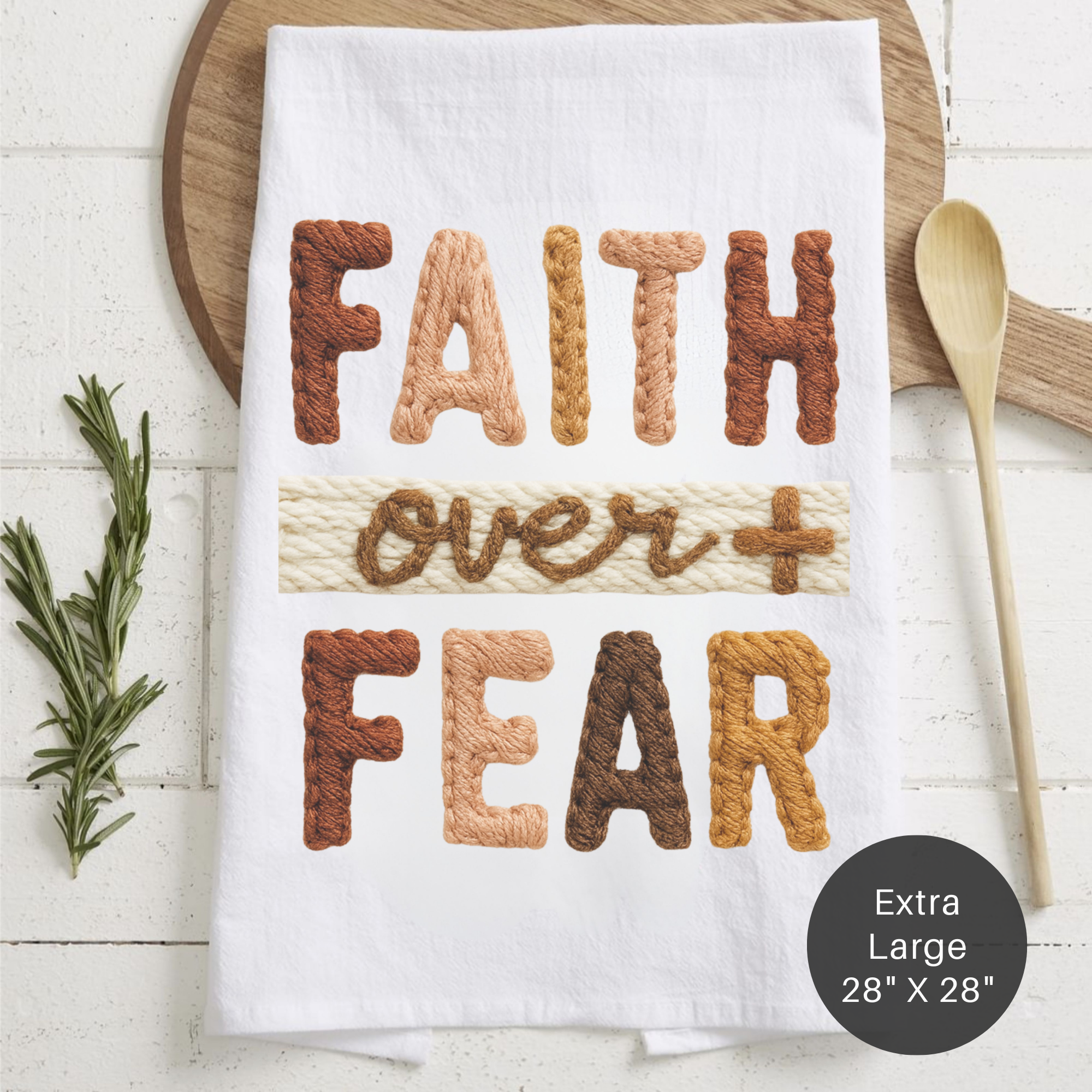 Tea towel with the design of kited text 'Faith Over Fear' on a counter with a wooden spoon.
