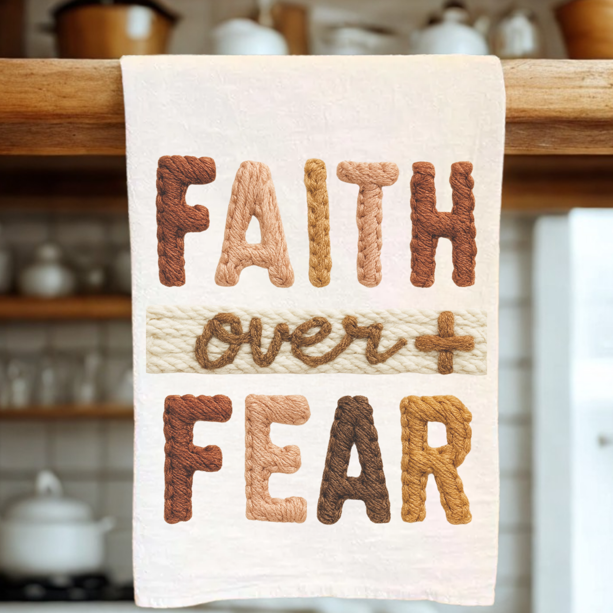 White tea towel with the knitted text design 'Faith Over Fear' hanging from a wooden rack.