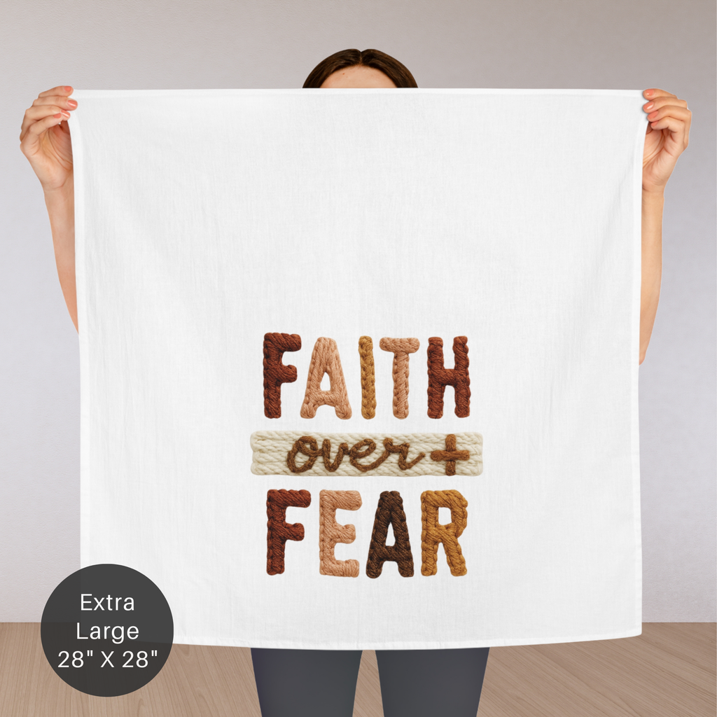 Person holding an extra large tea towel with the knitted text ' Faith Over Fear'