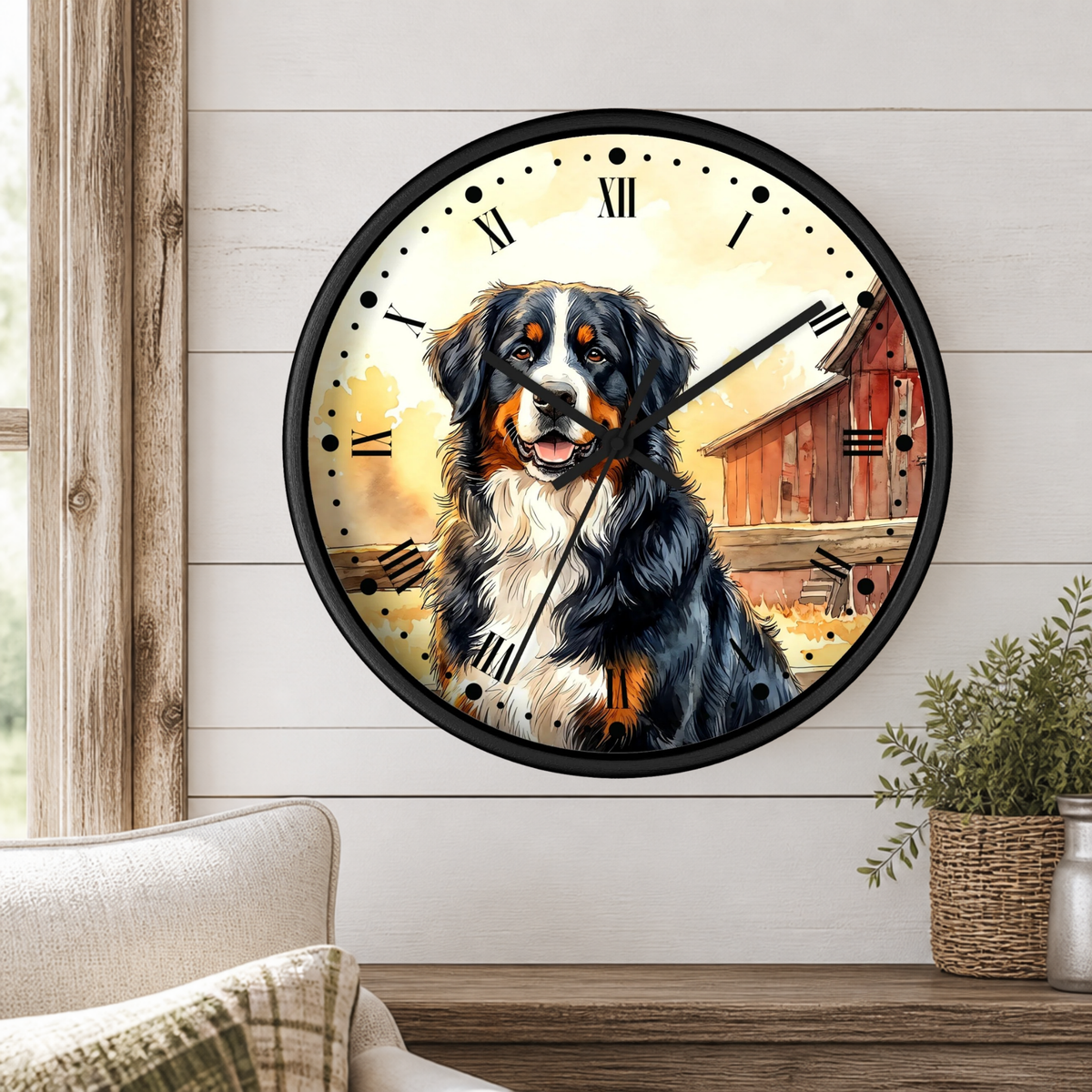 A round wall clock with a black frame and a printed illustration of a Bernese mountain dog in front of a barn, mounted on a white shiplap wall above a wooden table with a plant and part of a sofa visible.