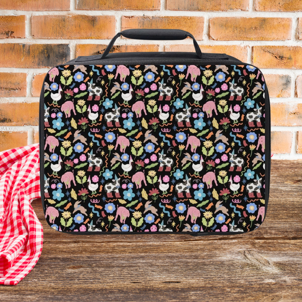 Patterned lunch bag with colorful animals and flowers on a wooden picnic table with a brick wall background