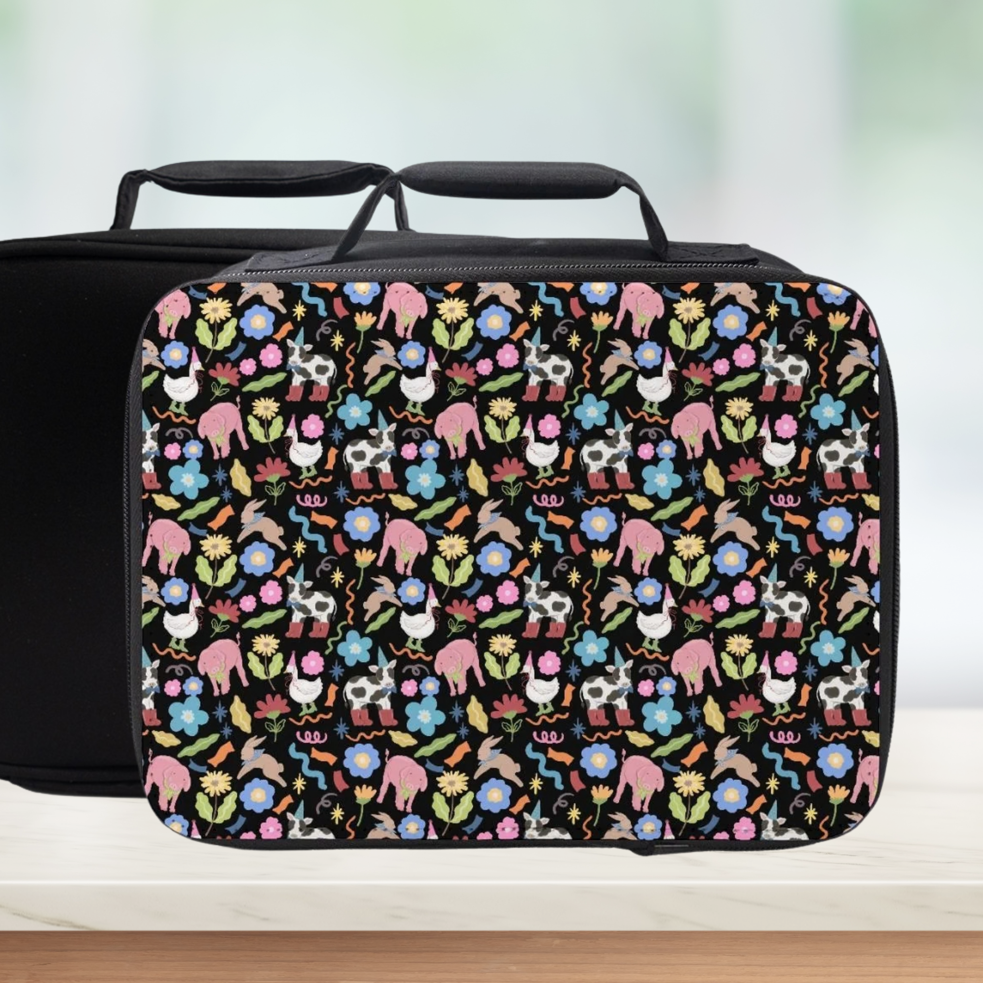 Black lunch bag with colorful farm animals and flower pattern on a white background