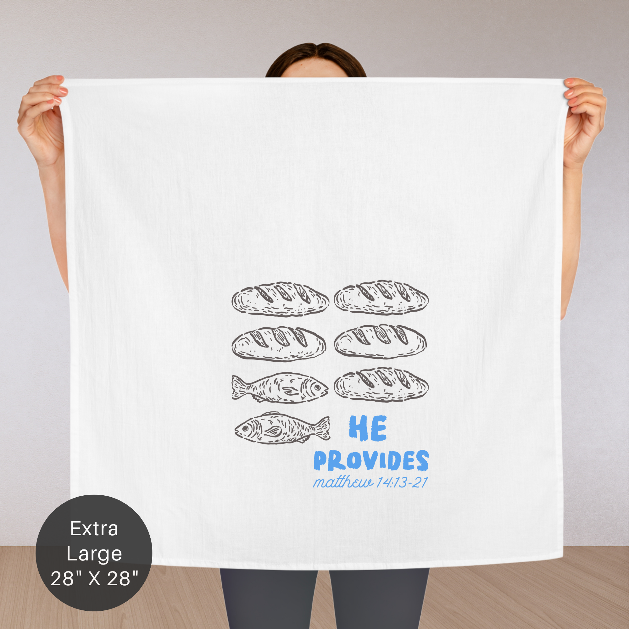 Person holding an extra large white tea towel with bread illustrations and text.