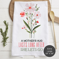 Floral-themed tea towel with text 'A Mother's Hug Last Long After She Lets Go' on a wooden surface