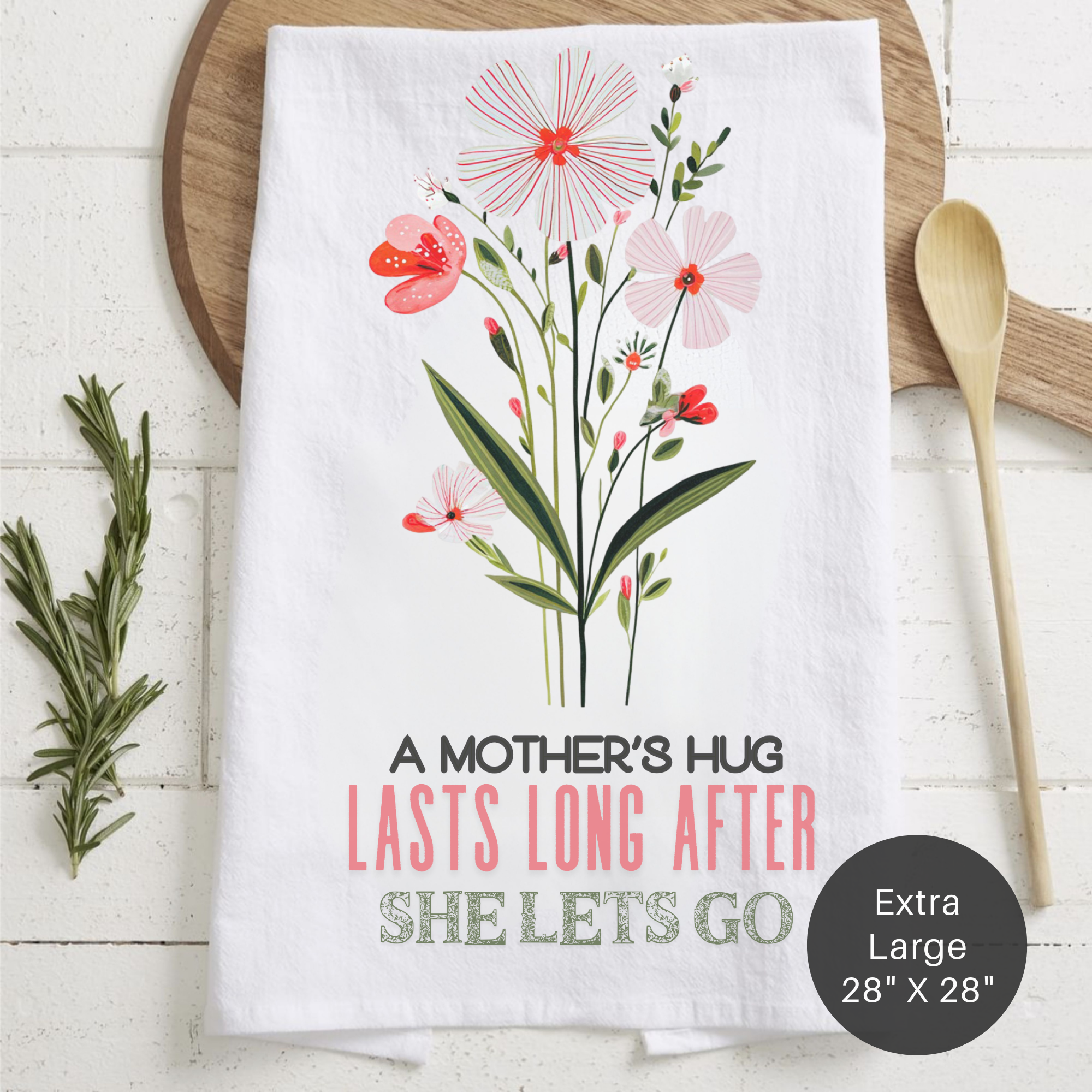 Floral-themed tea towel with text 'A Mother's Hug Last Long After She Lets Go' on a wooden surface