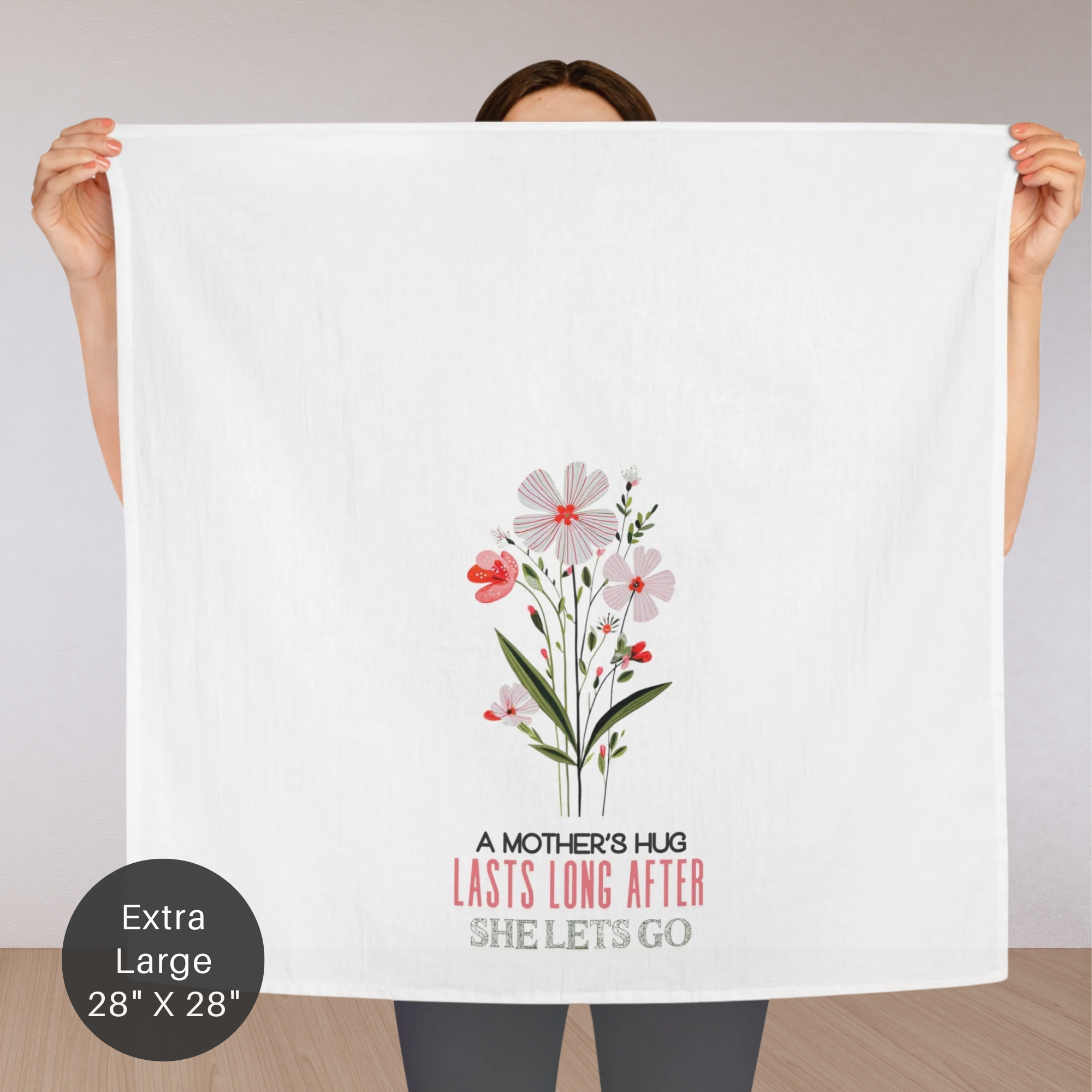 Person holding an extra large tea towel with floral design and text.