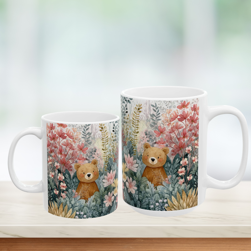 Two mugs with teddy bear and floral design on a white surface.