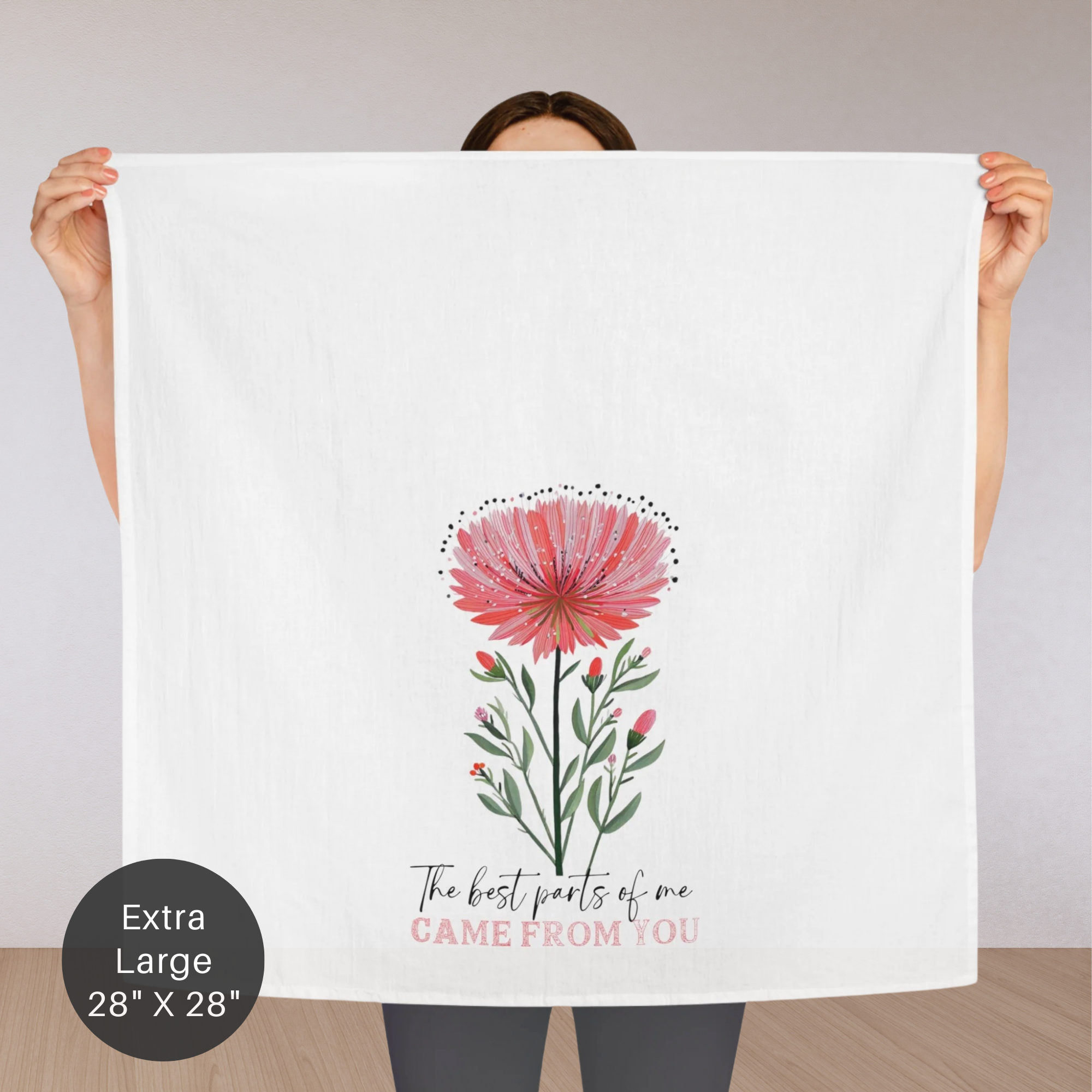 Person holding an extra large white tea towel with a floral design and text.