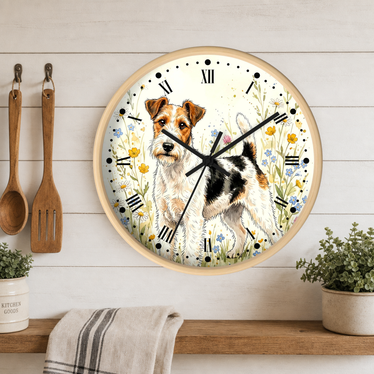 A round wall clock with a light wood frame hangs on a white wood-paneled wall above a shelf. The clock face features a watercolor illustration of a terrier dog surrounded by yellow and blue flowers.