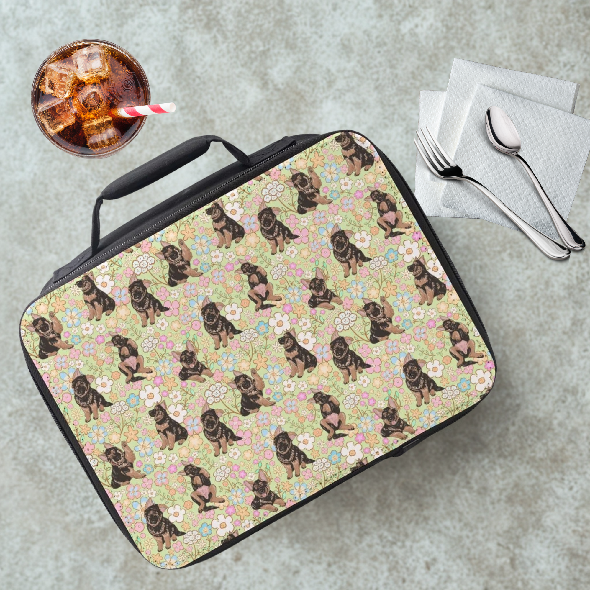 Lunch bag with hand drawn German shepherd dog and flowers pattern on a cafeteria table with a drink and utensils