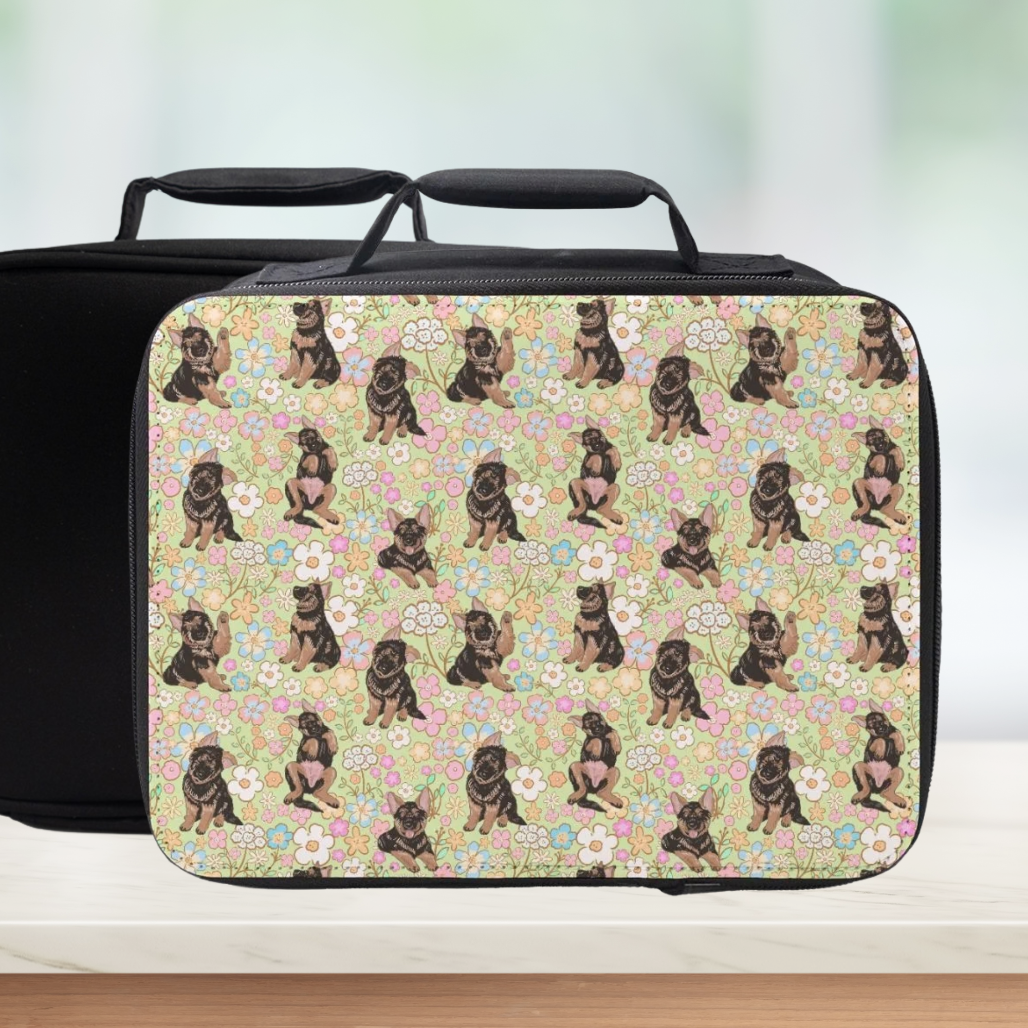 Black lunch bag with a hand drawn pattern of puppy dogs and flowers on a light background