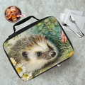 Lunch bag with a hedgehog design on a table with a drink and utensils.