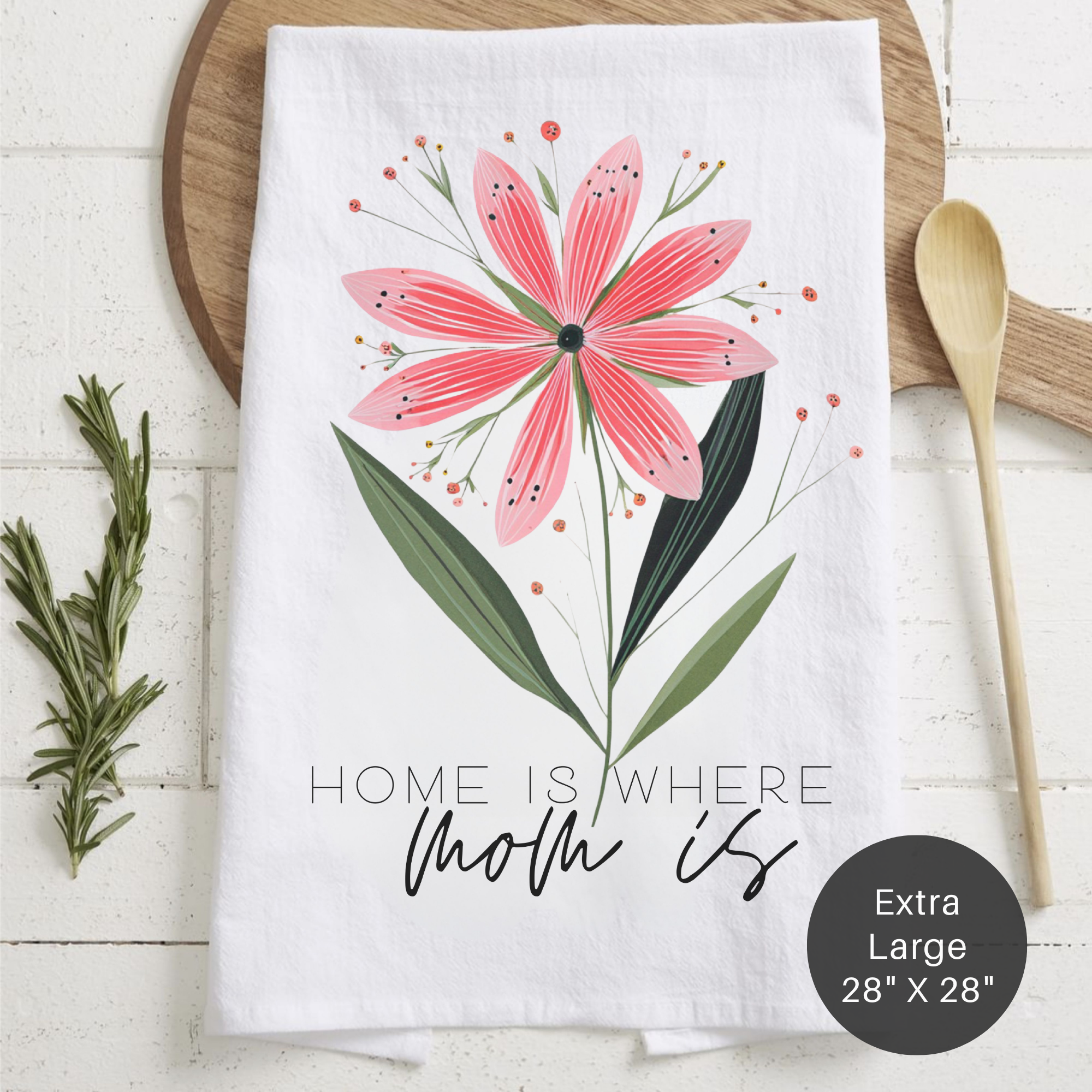 Floral towel with a pink flower design and text 'Home Is Where Mom Is' on a wooden surface.