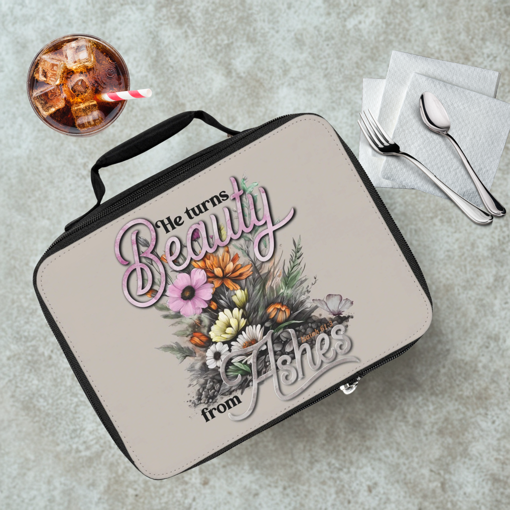 Lunch box with floral design and text on a cafeteria table with a drink and utensils.