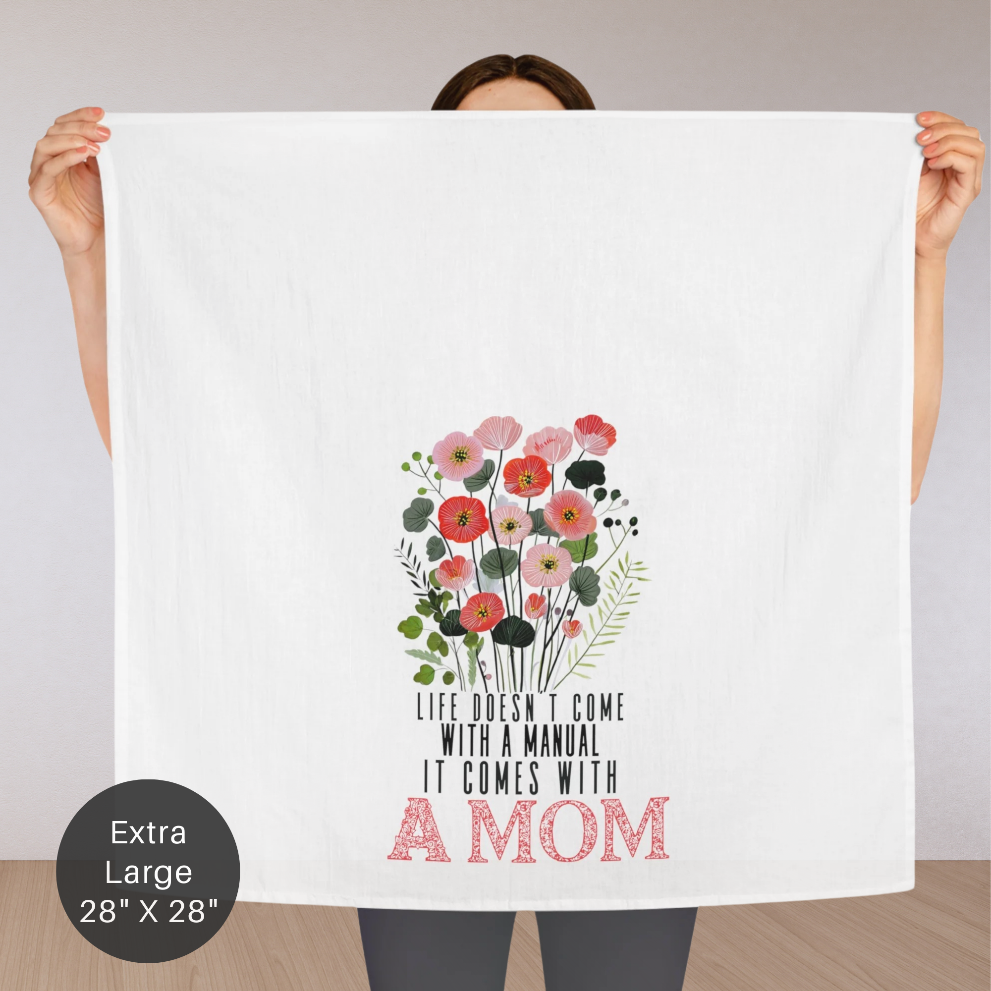 Person holding an extra large tea towel with floral design and text ' Life Doesn't Come With A Manual It Comes With A MOM'