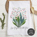 Floral design towel with 'Love Begins With You' text on a wooden surface.