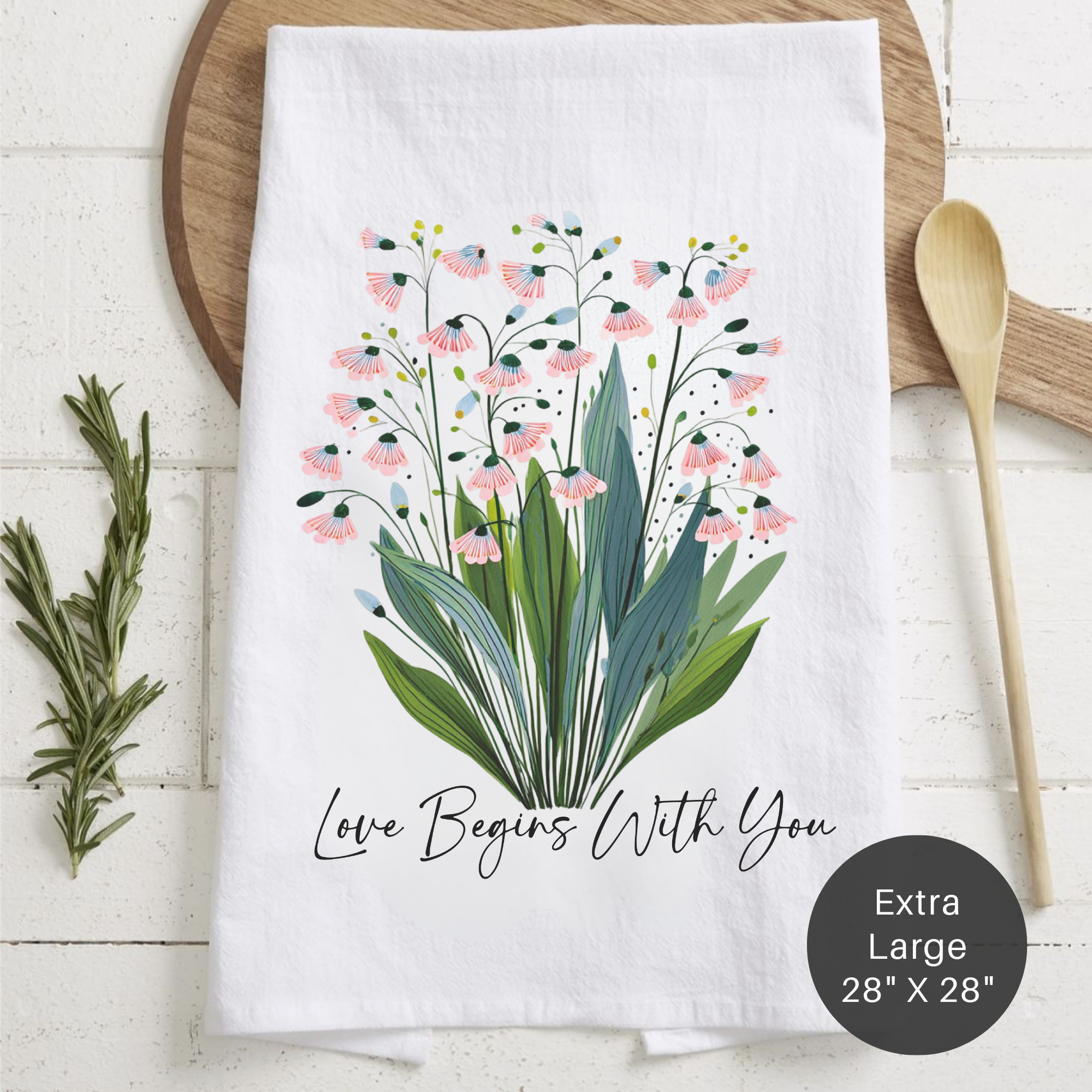 Floral design towel with 'Love Begins With You' text on a wooden surface.