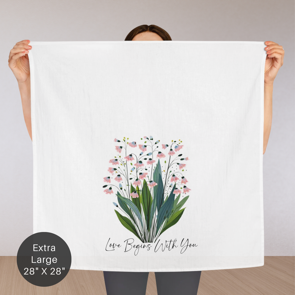 Person holding an extra large white tea towel with floral design and text.