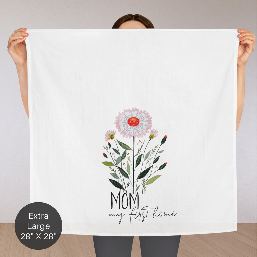 Person holding an extra large white tea towel with floral design and text 'Mom My First Home'.