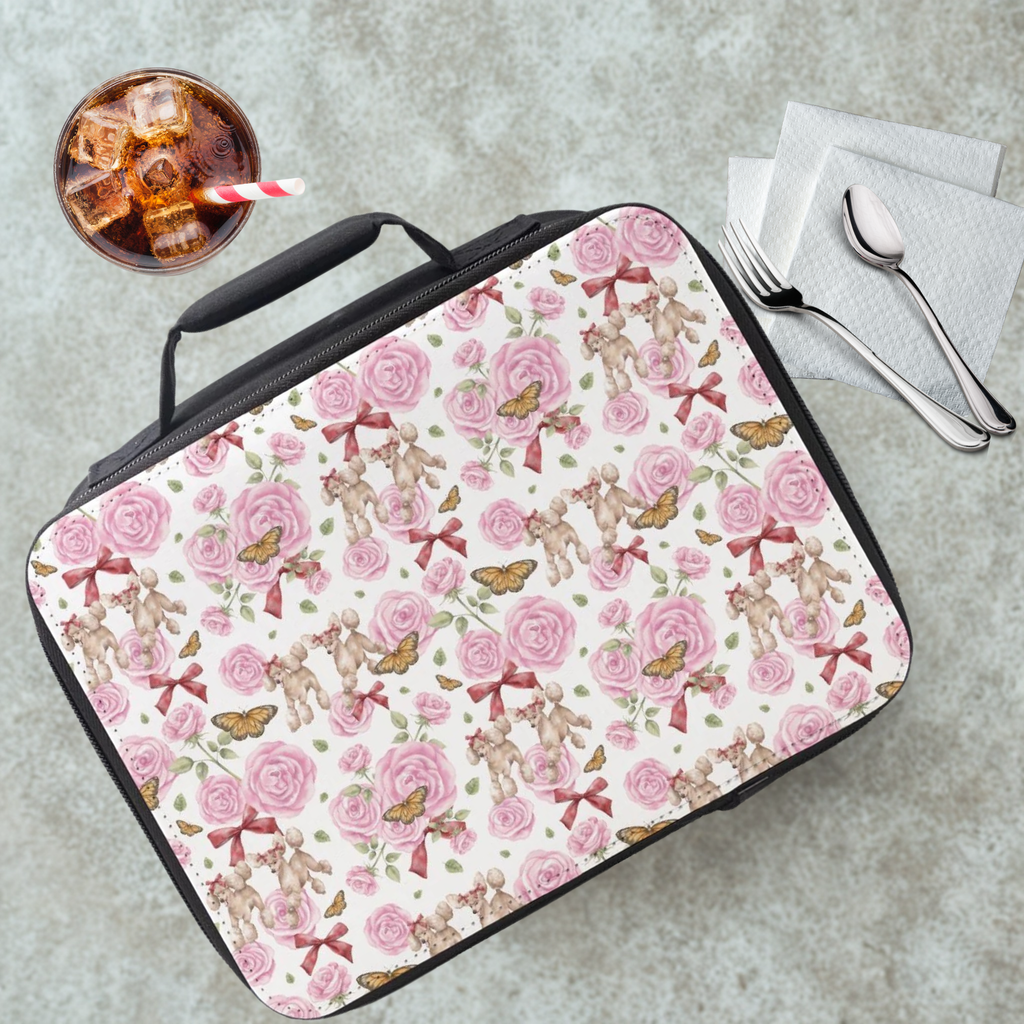 Lunch bag with poodle dogs, roses, butterflies, and bows pattern on a cafeteria table with a drink and utensils.