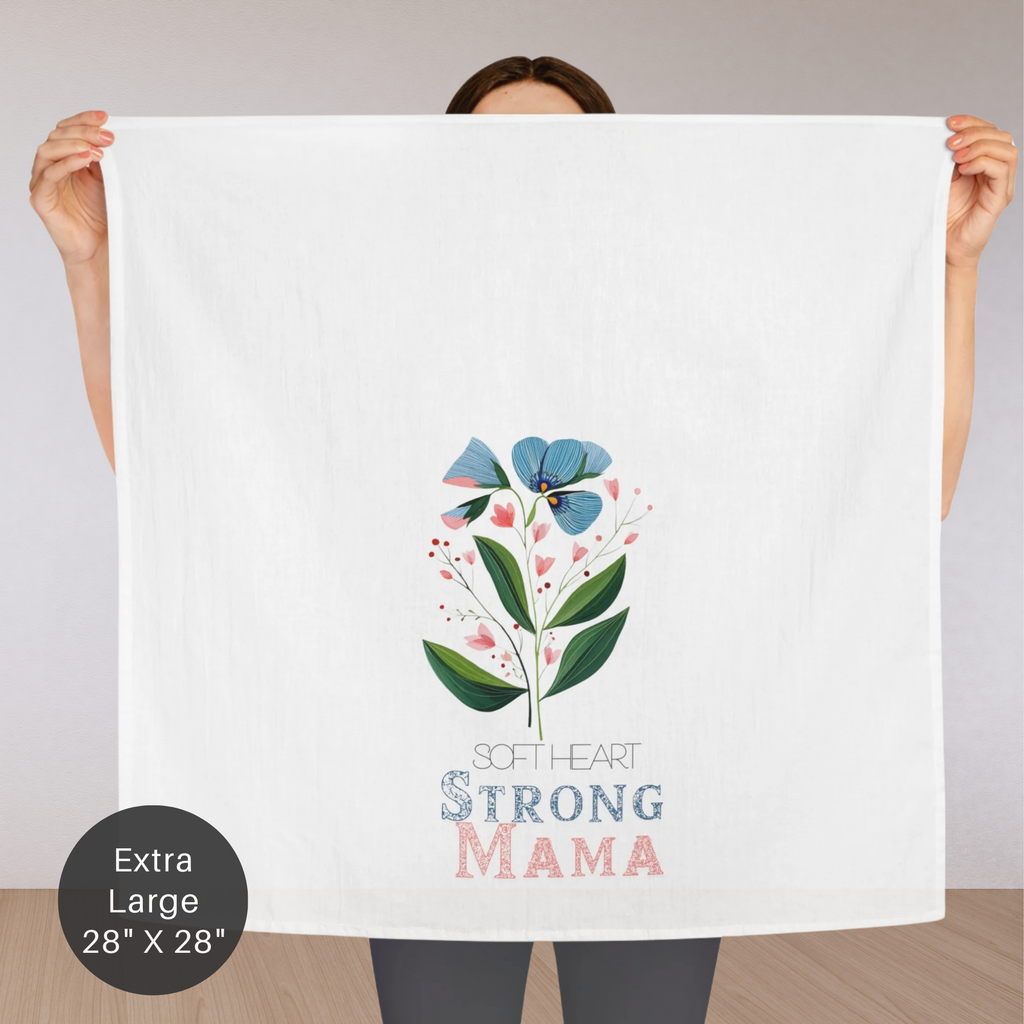 Person holding an extra large cotton tea towel with floral design and text 'Soft Heart Strong Mama' on a plain background
