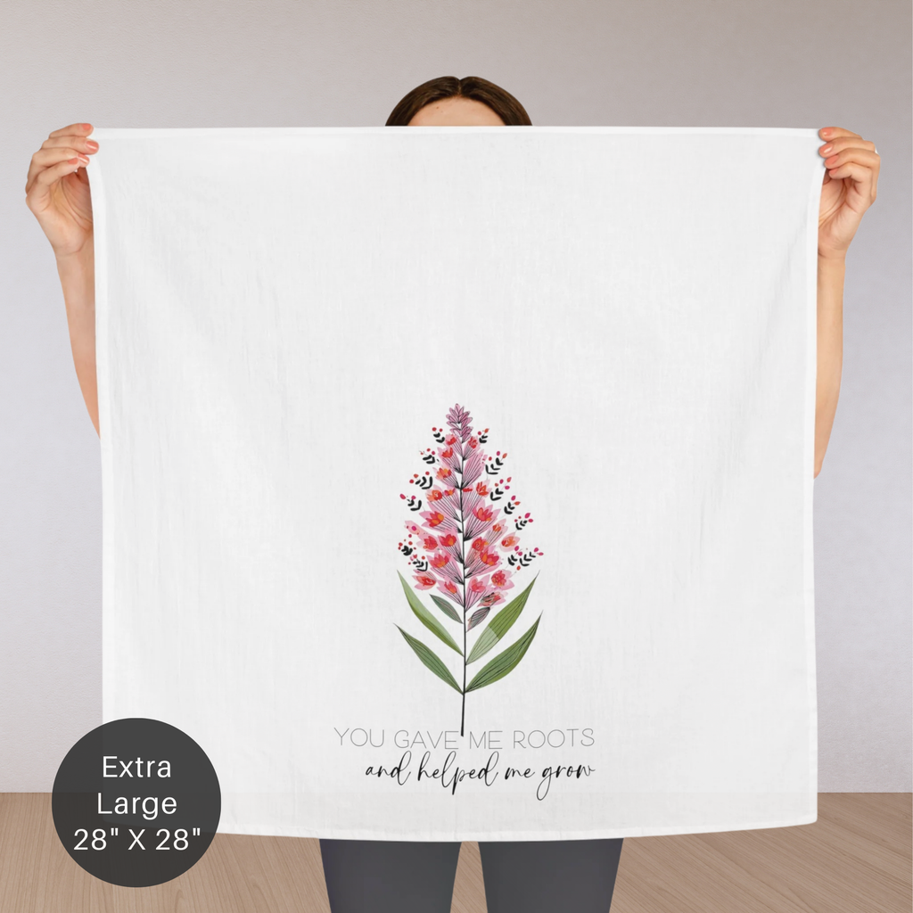 Person holding an extra large white tea towel with a floral design and text.