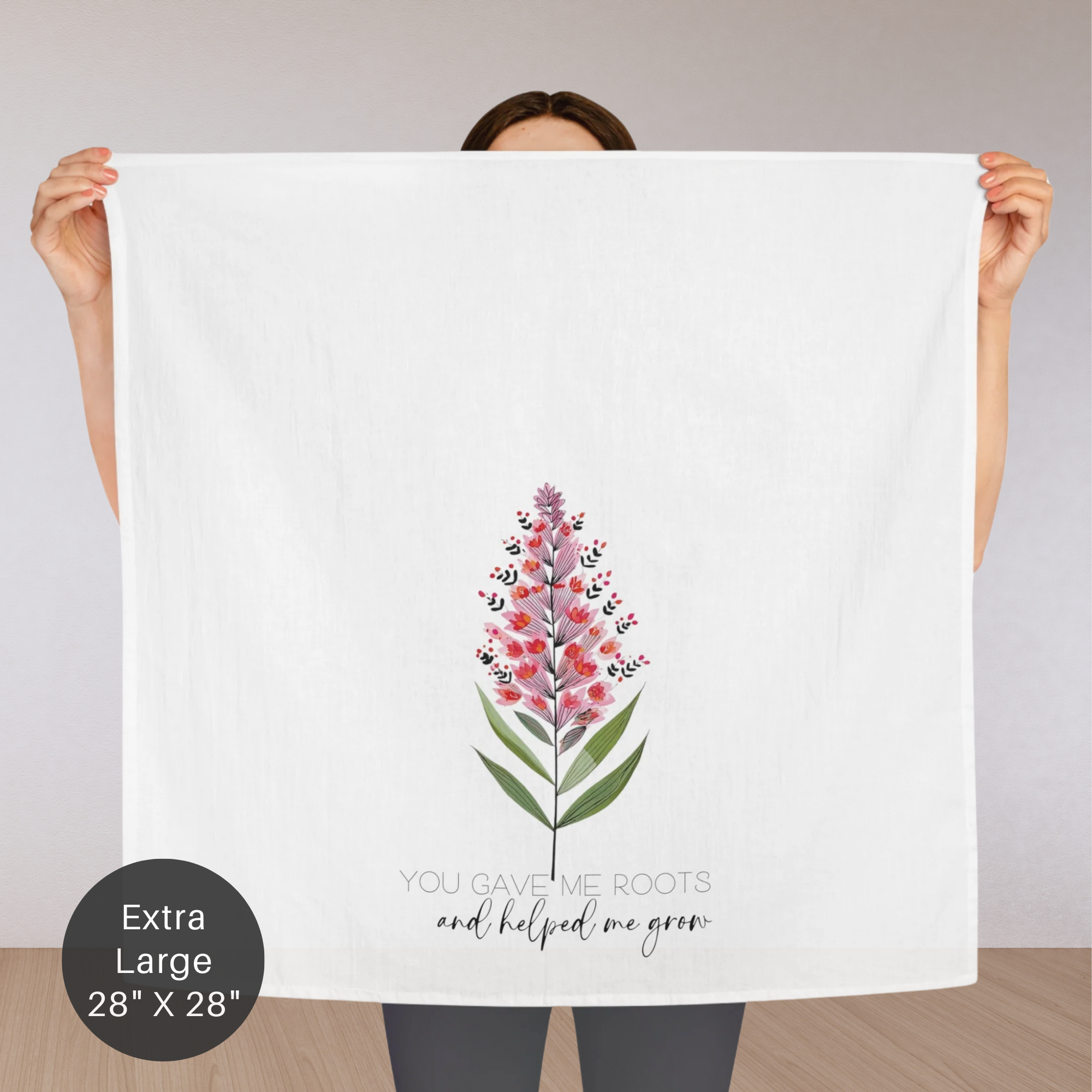 Person holding an extra large white tea towel with a floral design and text.