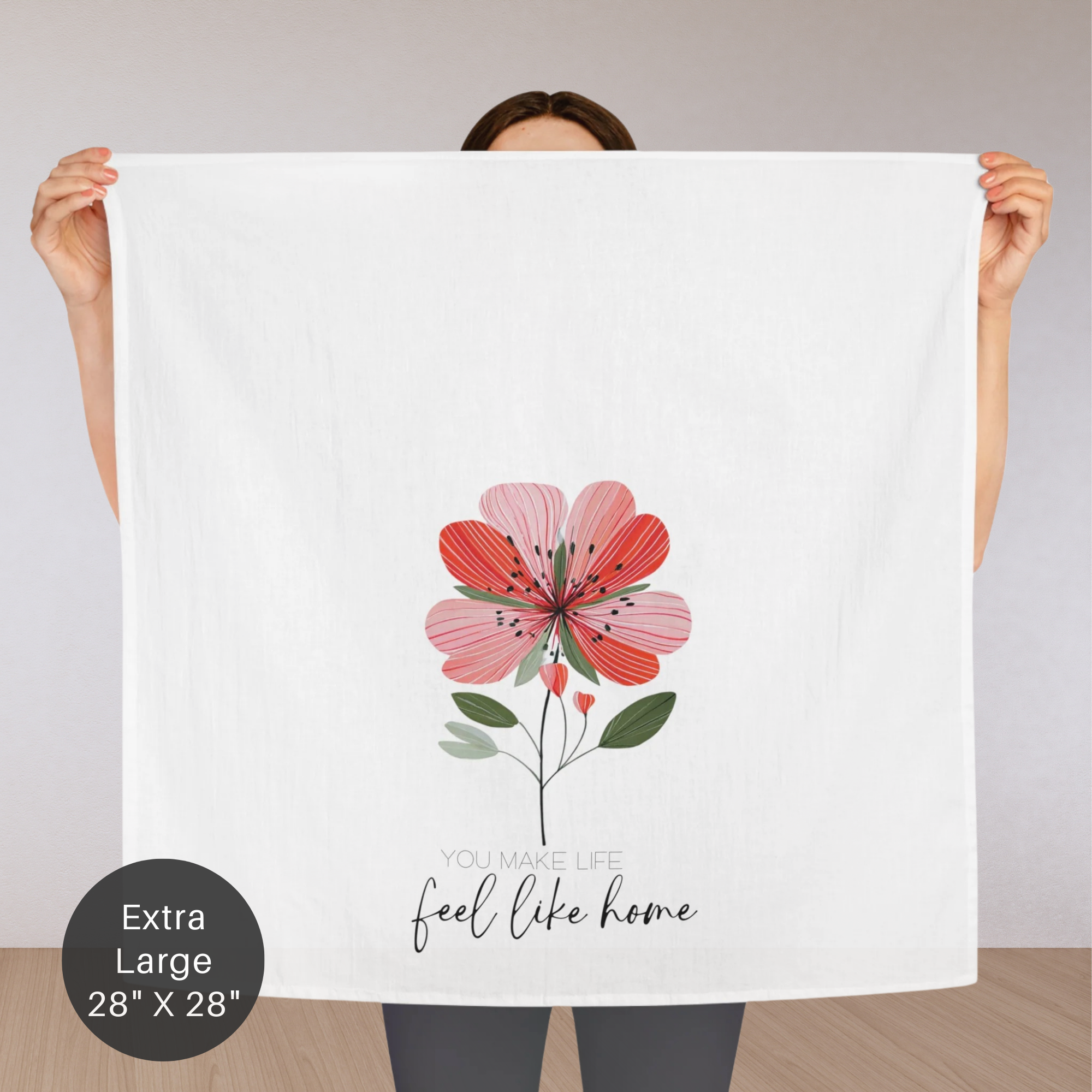 Person holding an extra large white tea towel with a red floral design and text.