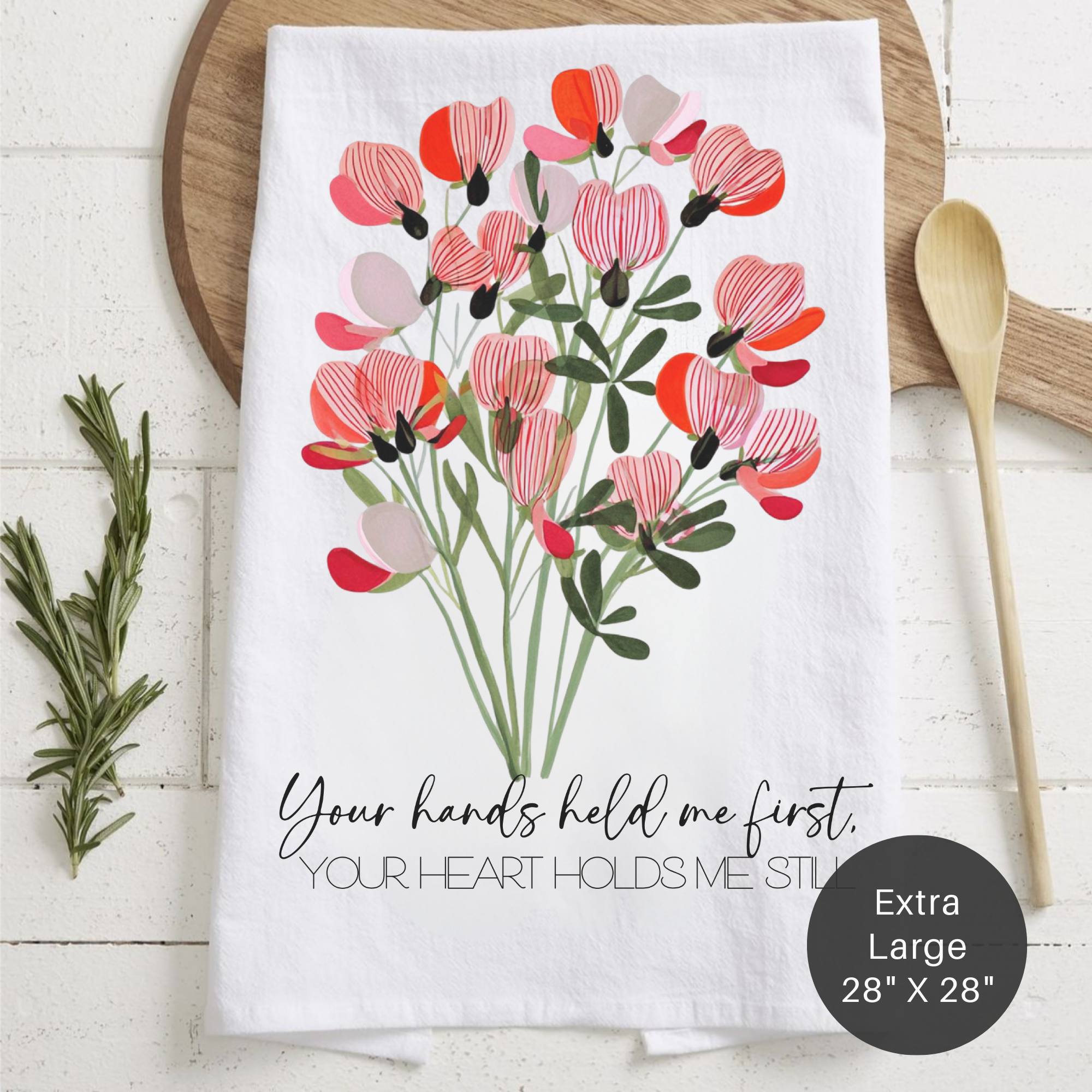 Floral design towel with text 'Your Hands Held Me First Your Heart Holds Me Still' on a wooden surface