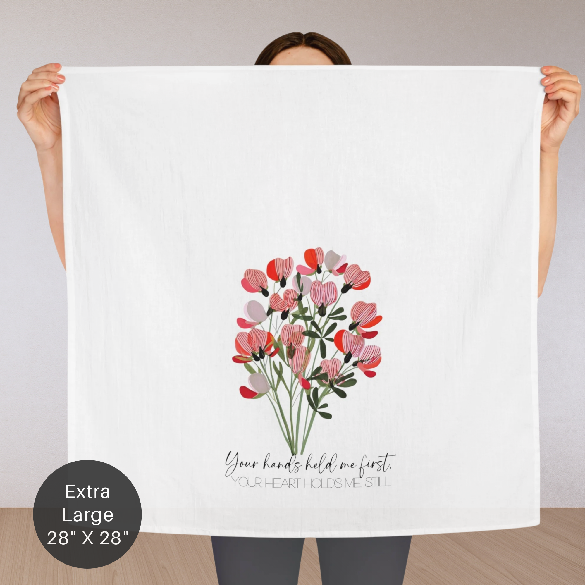 Person holding an extra large towel with floral design and text.