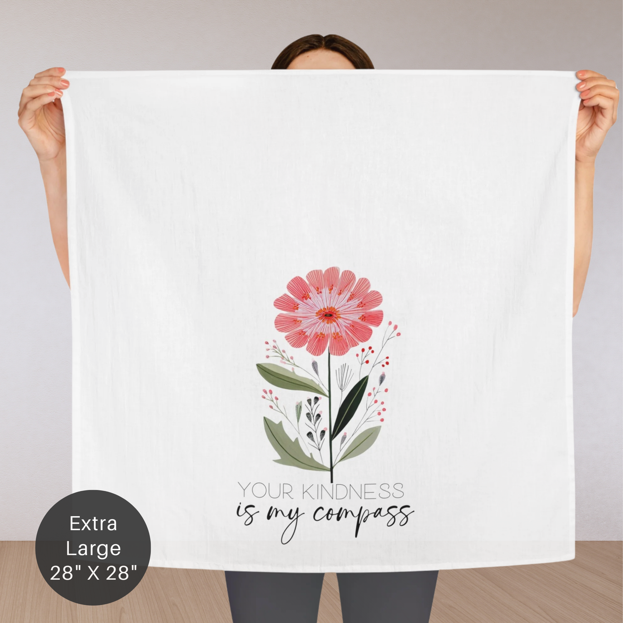 Person holding an extra large white tea towel with a pink flower design and text.